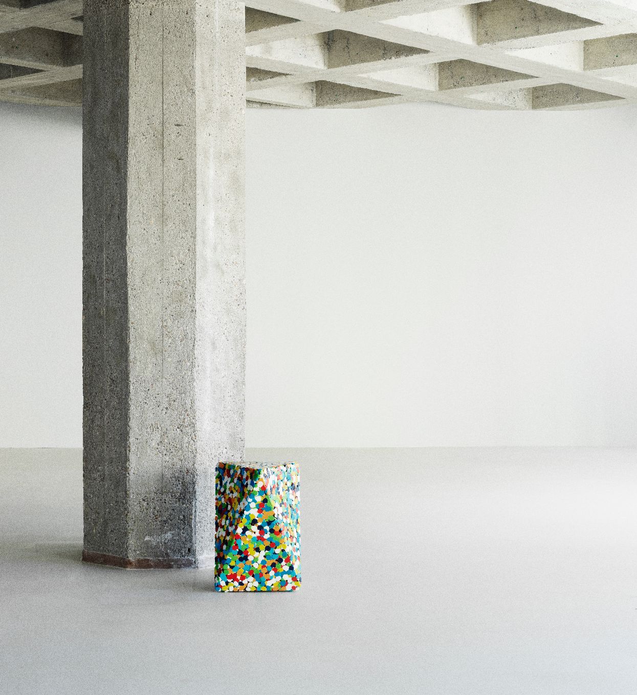 Delta Proust Beistelltisch von Normann Copenhagen, mehrfarbig, neben einem Betonpfeiler in einem minimalistischen Raum.