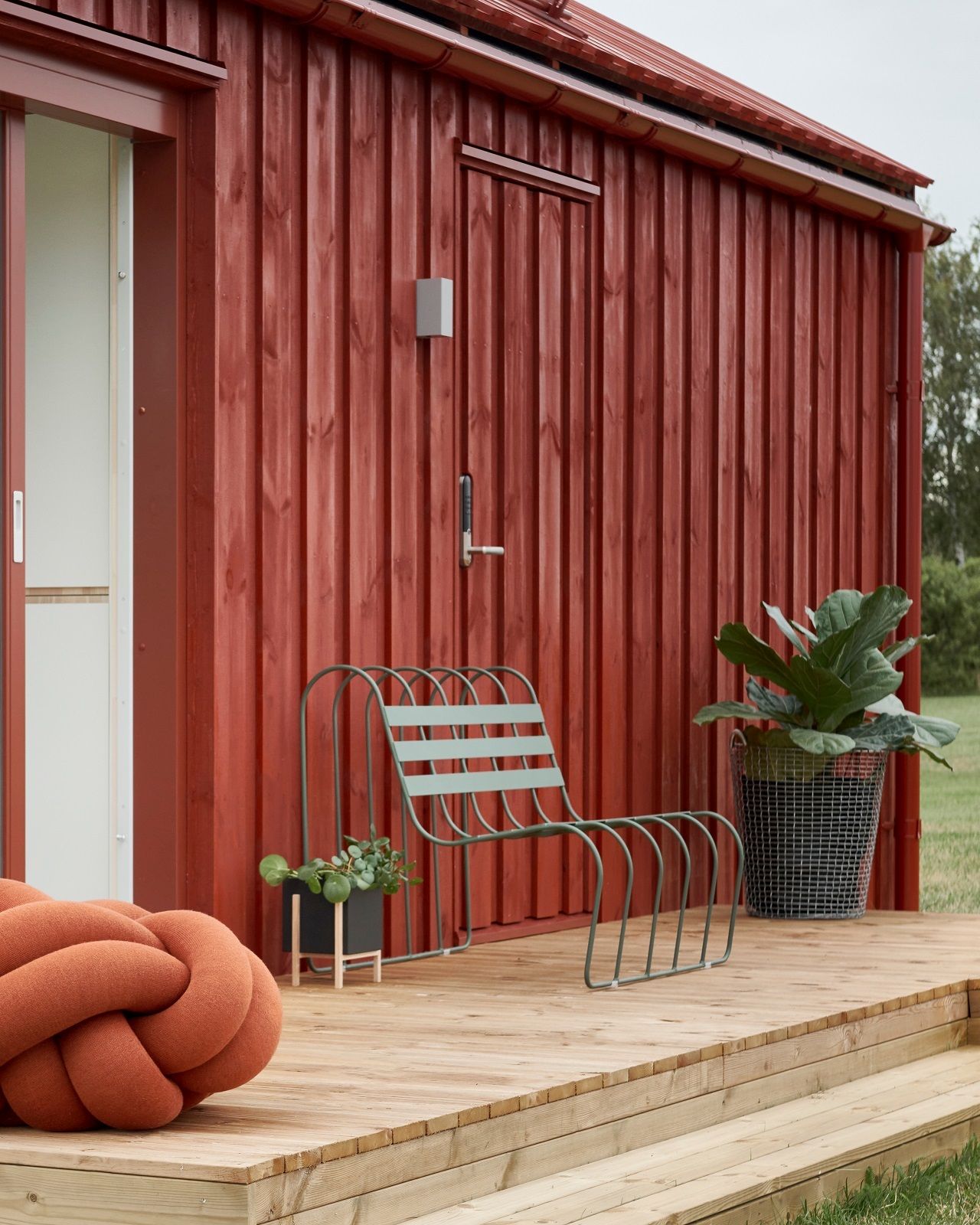 Gardener's Sofa von Design House Stockholm auf Holzterrasse vor rotem Haus. Outdoor Möbel.