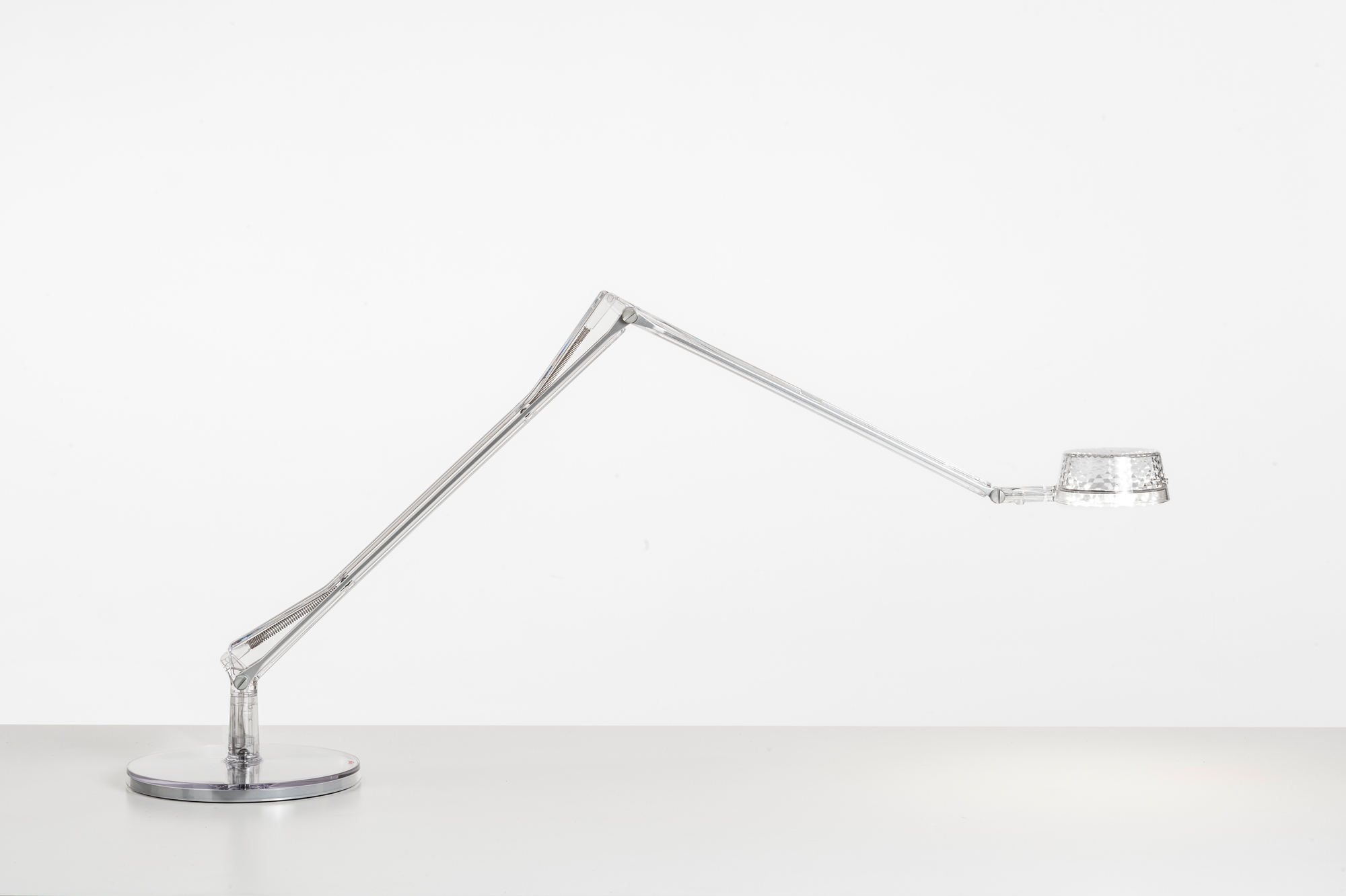 Aledin Tischleuchte von Kartell, moderne LED Schreibtischlampe mit transparentem Gestell und rundem Fuß.