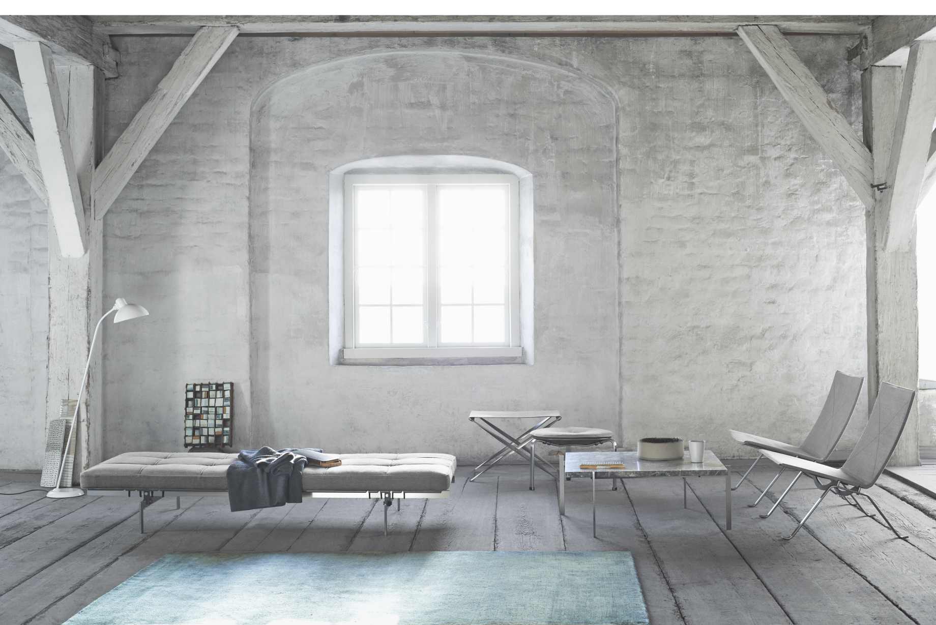 Helle Raumansicht mit Fritz Hansen PK80 Liege, Poufs, Marmortisch und Teppich auf Holzdielenboden.