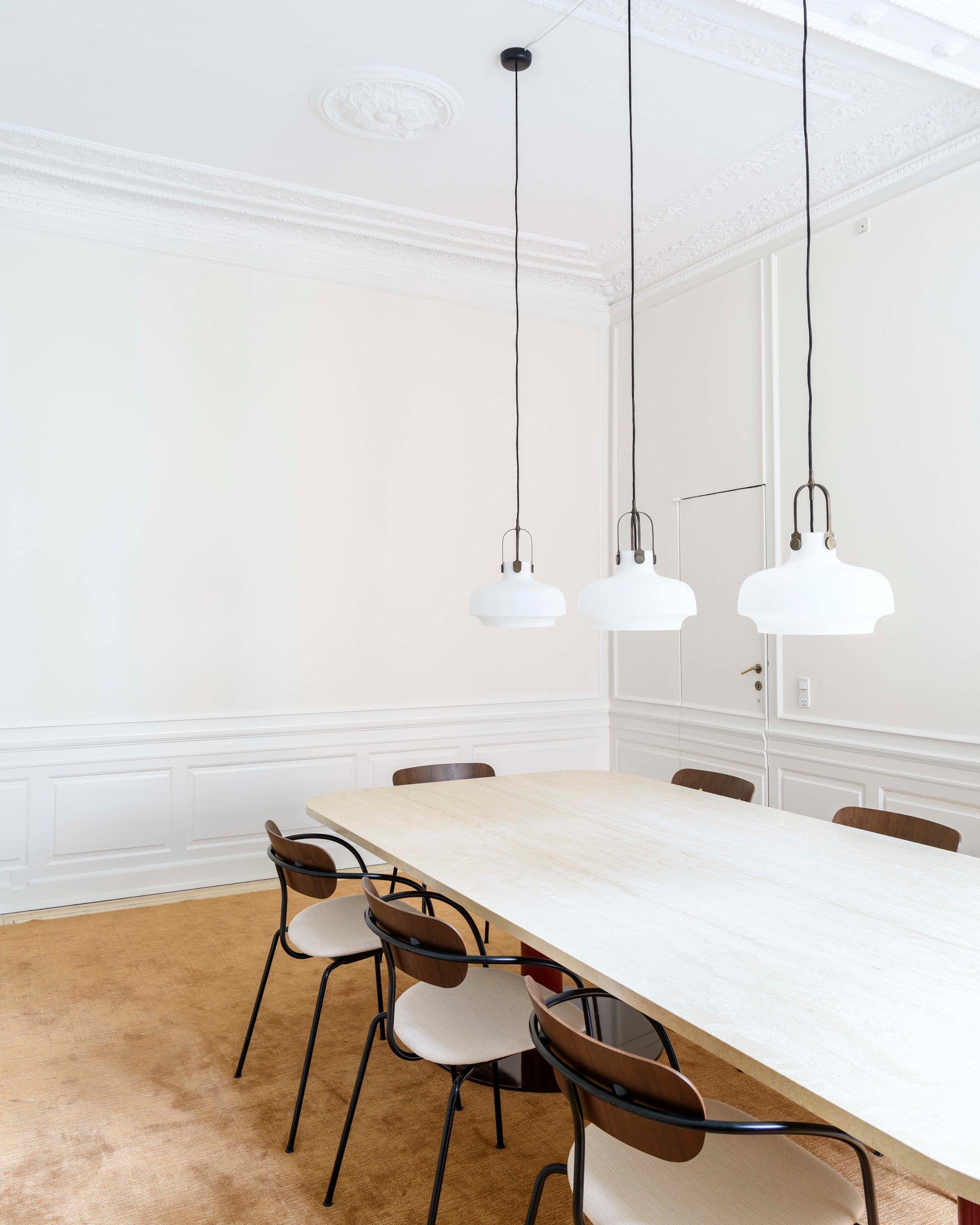 Esszimmer mit Esstisch, Stühlen und drei weißen Copenhagen SC6 Pendelleuchten von AndTradition über dem Tisch.