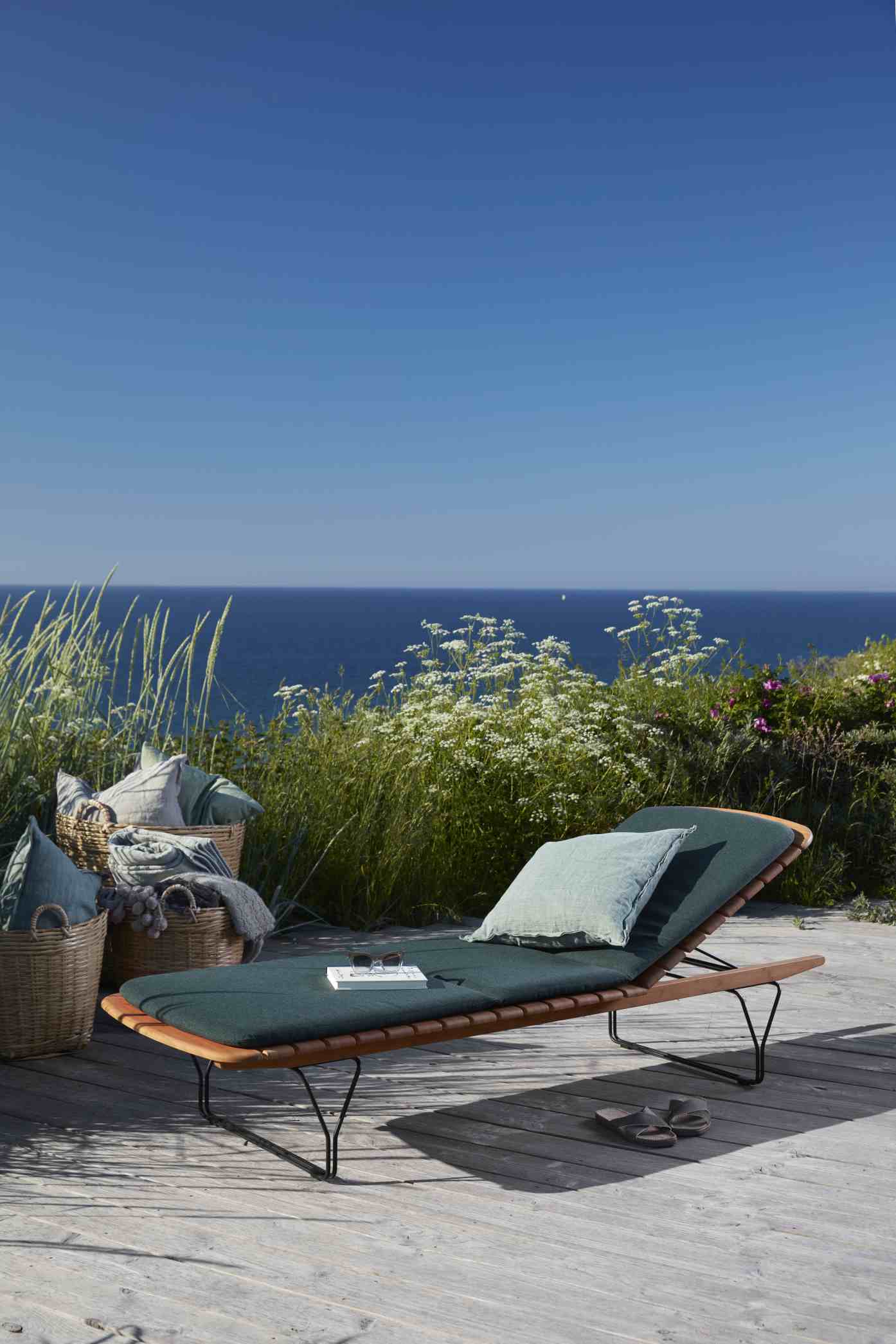 Houe Sonnenliege mit Molo Outdoor Kissen in Grün vor Meer und Dünenlandschaft für entspannte Stunden.