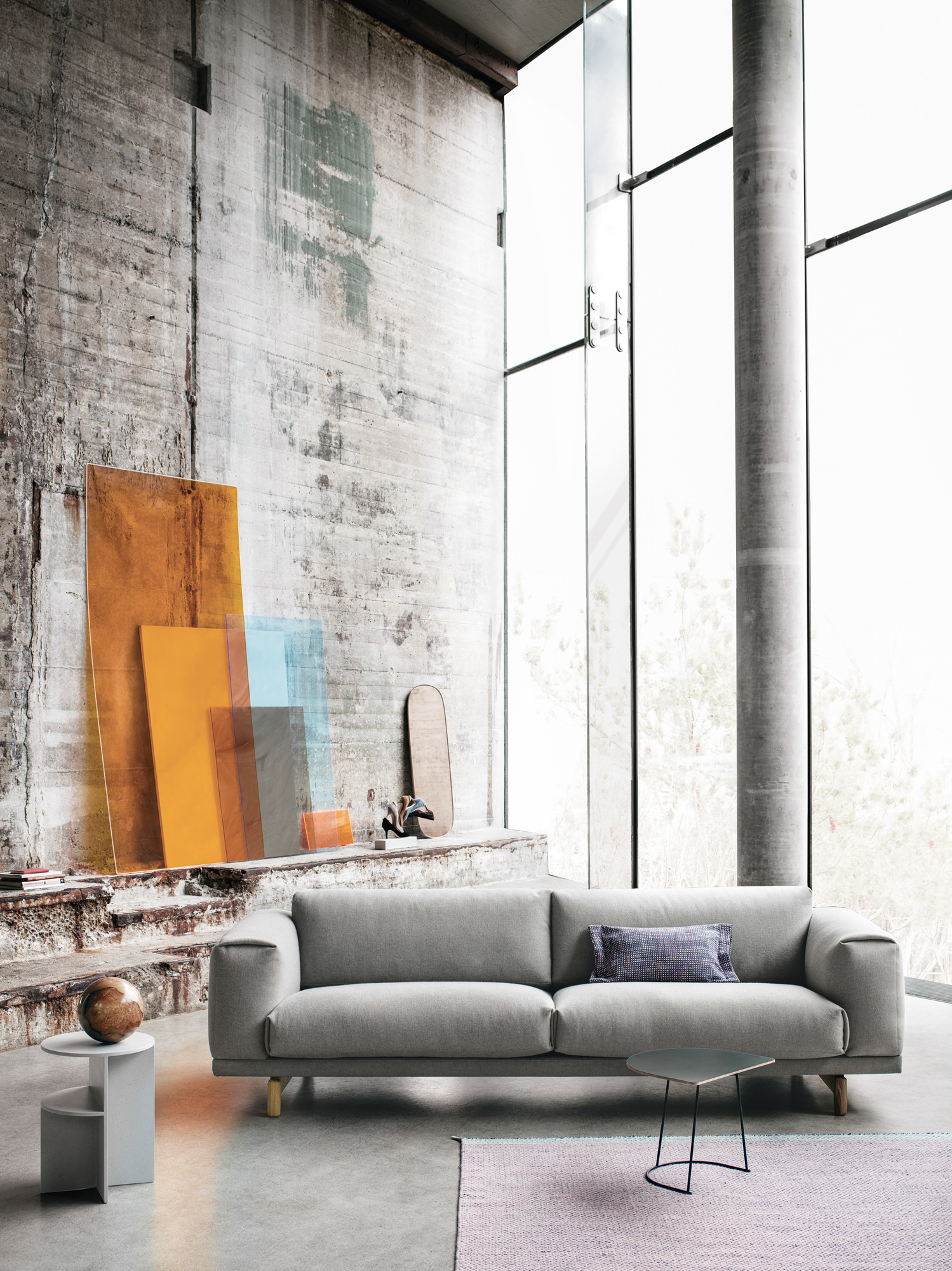 Heller Wohnraum mit grauem Sofa, Muuto Airy Coffee Table Beistelltisch und kleinem, dunklen Couchtisch auf einem Teppich.