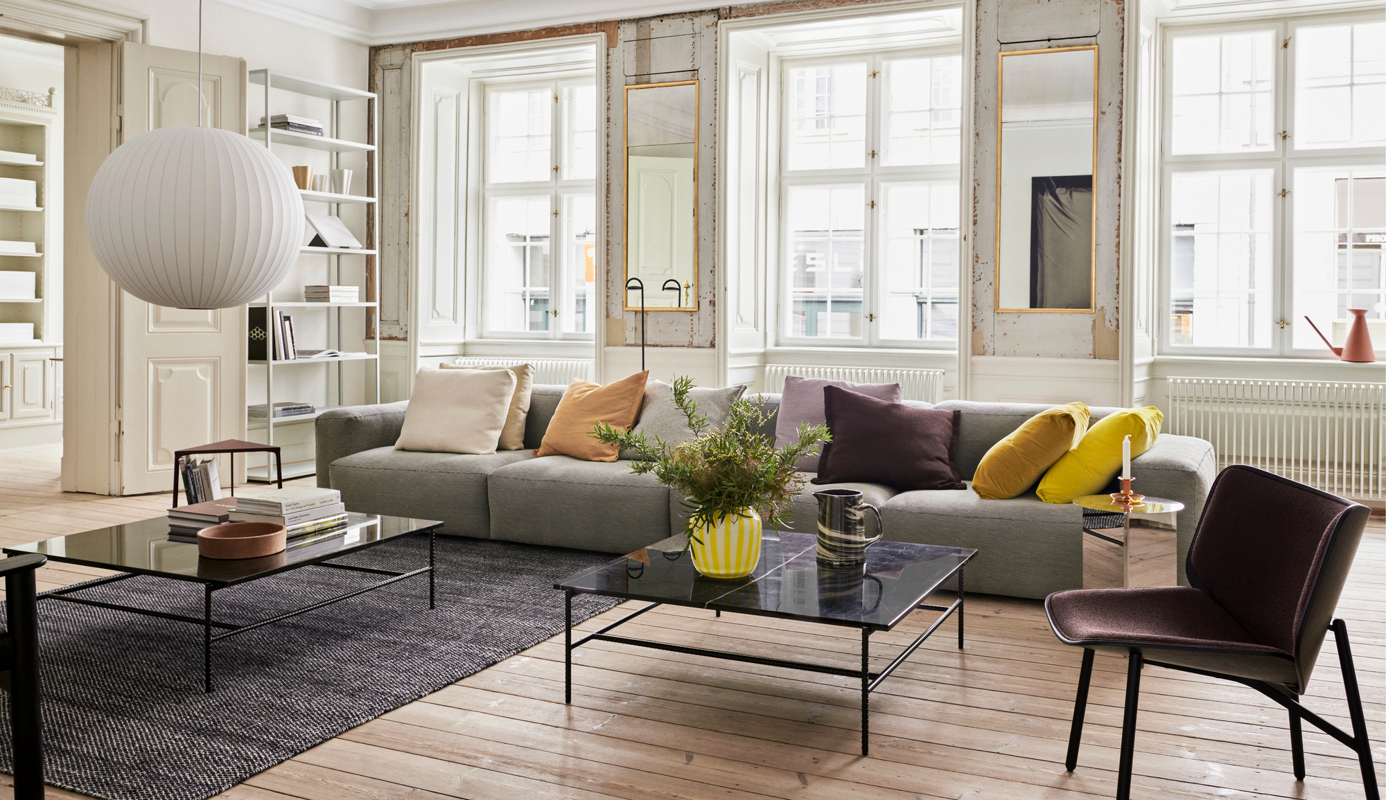 Heller Wohnraum mit grauem Sofa, Couchtisch, Teppich und braunem Dapper Lounge Chair Sessel von Hay.