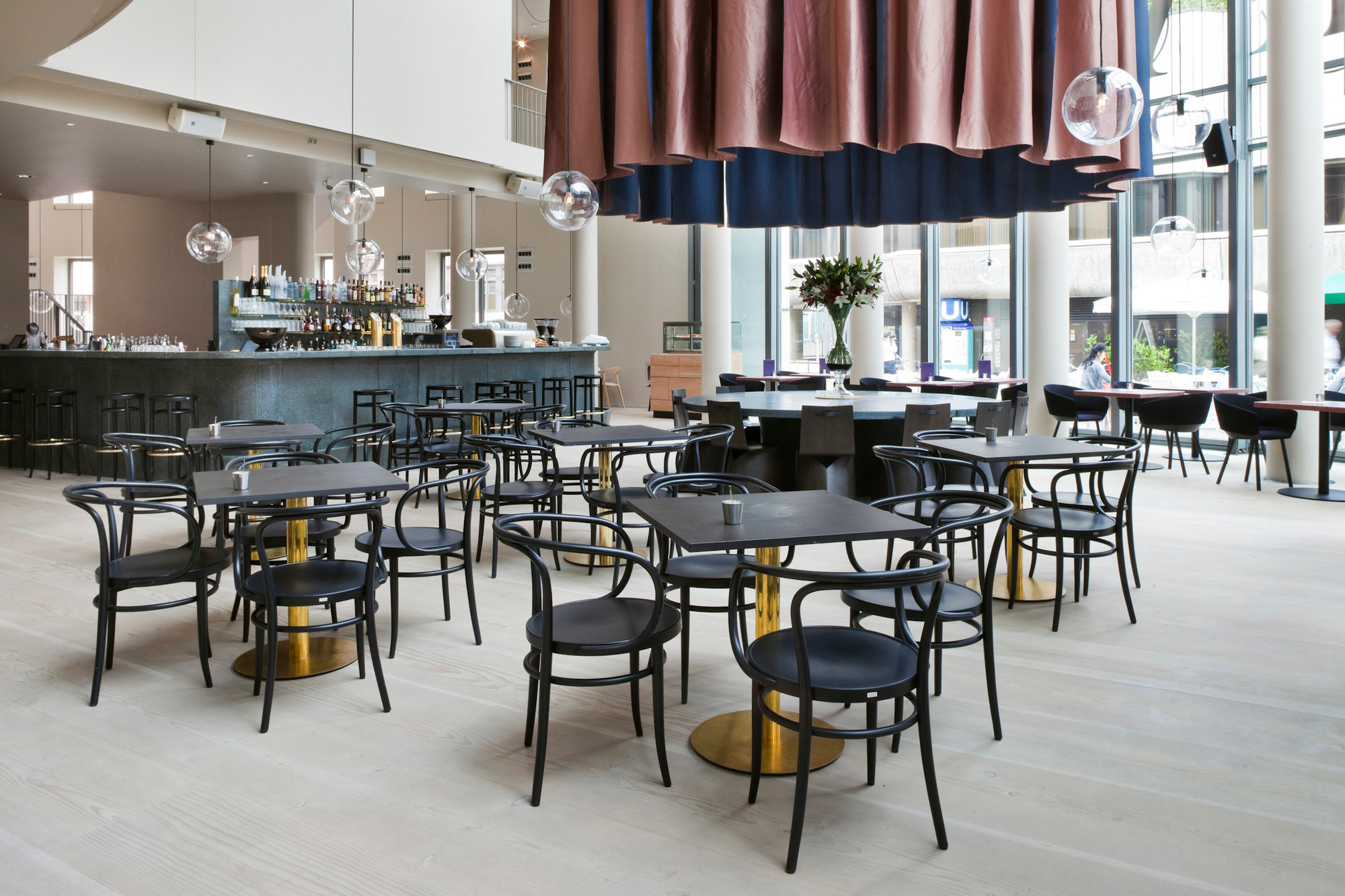 Innenansicht eines Restaurants mit vielen schwarzen 209 Bugholz Thonet Stühlen und Tischen.