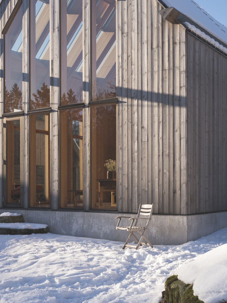 Selandia Armchair Outdoor Sessel von Skagerak by Fritz Hansen im winterlichen Garten vor Holzhaus.