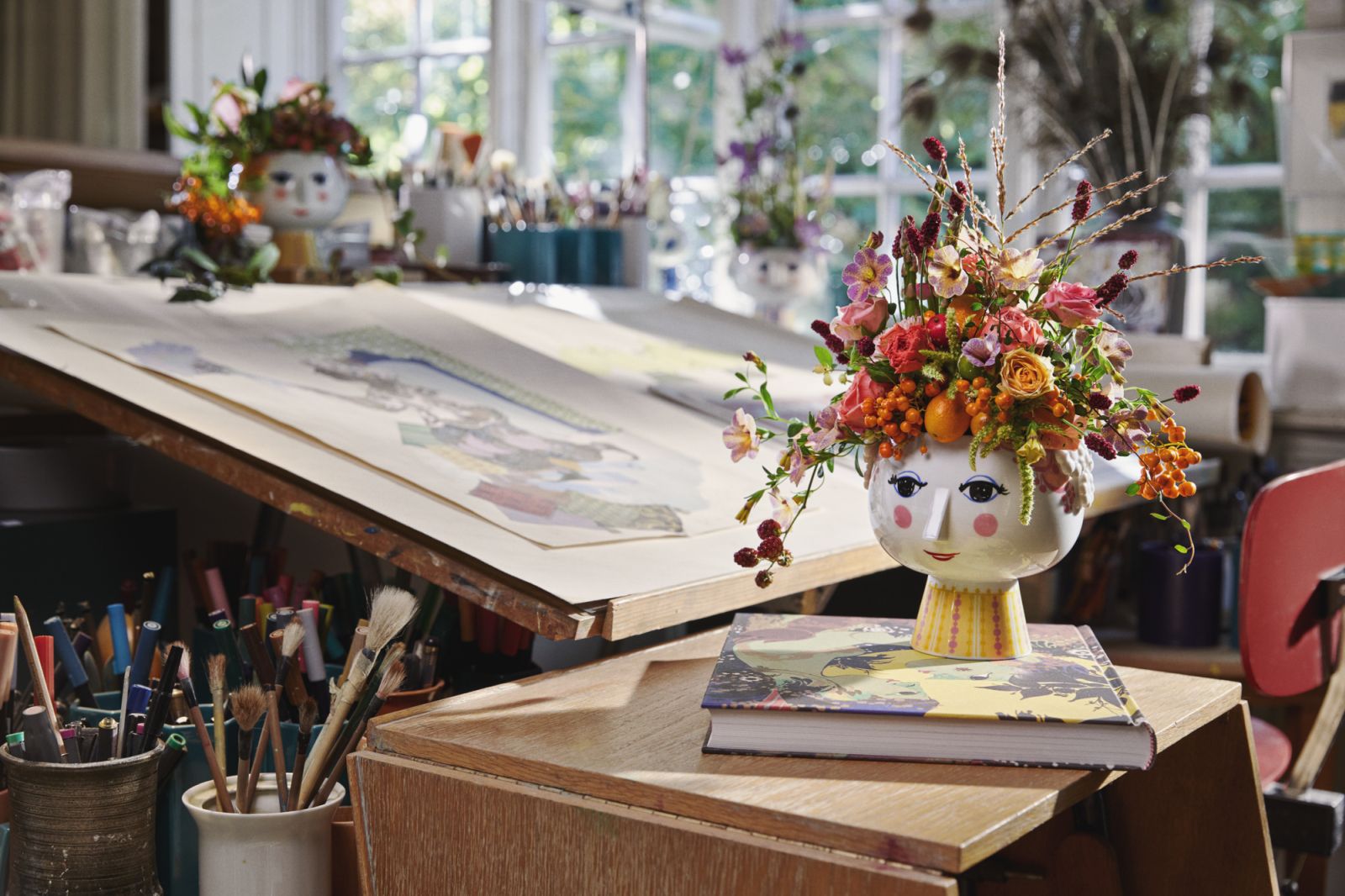 Nahaufnahme des Eva Übertopfs von Bjørn Wiinblad, gefüllt mit bunten Blumen auf einem Tisch im Atelier.