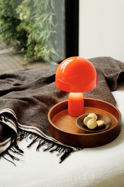 Orangefarbene Bell LED Tischleuchte von Tom Dixon auf einem Holztablett mit Keksen.