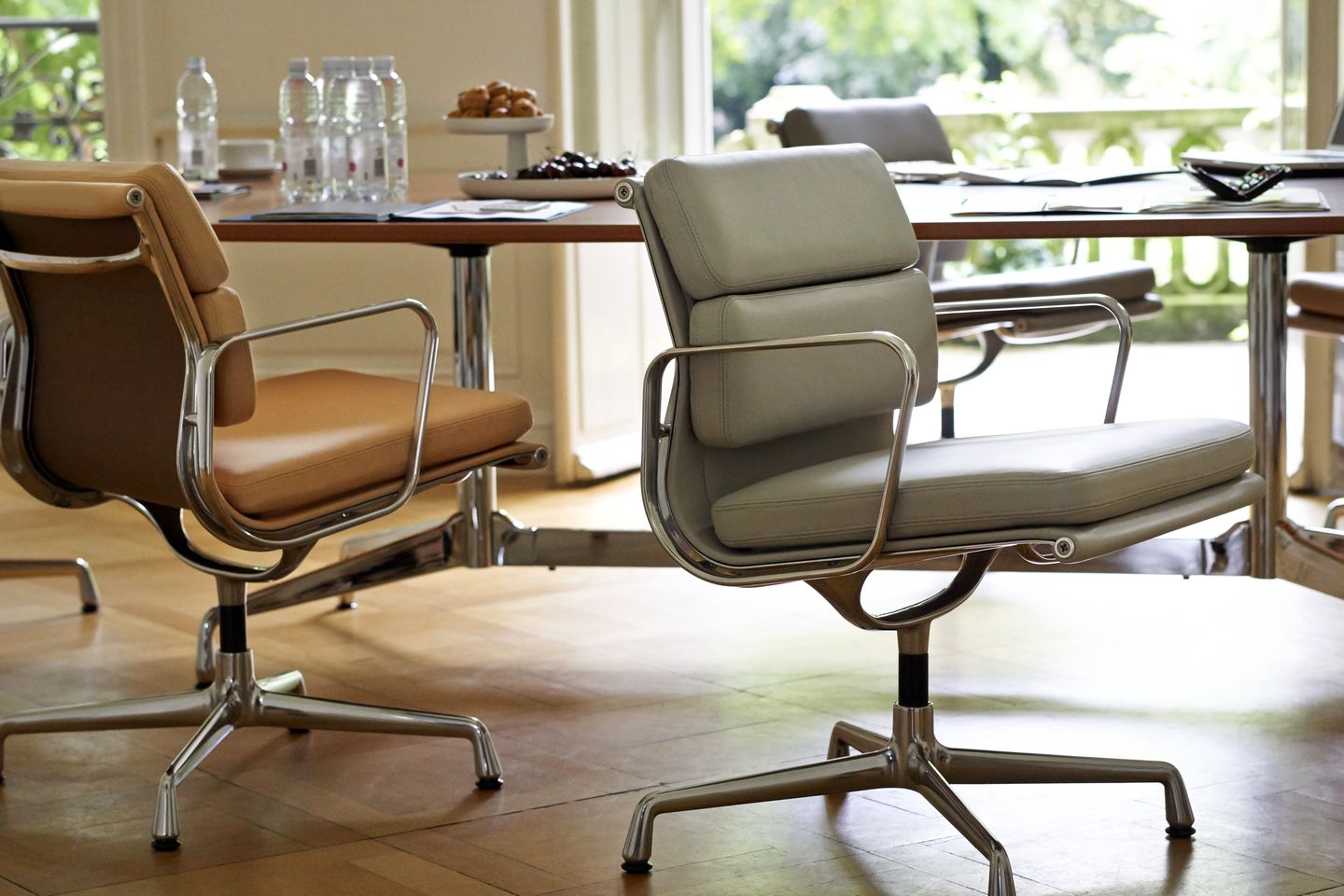 Nahaufnahme von zwei Vitra EA 207 Soft Pad Sesseln in Beige und Grau im Konferenzraum.
