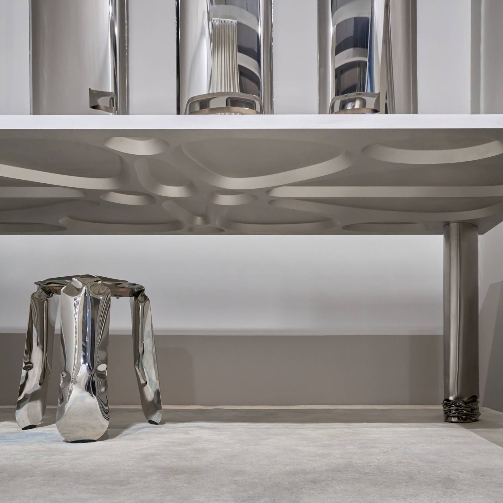 Detailaufnahme des Crash Table Esstischs von Zieta mit passendem Hocker aus poliertem Stahl.