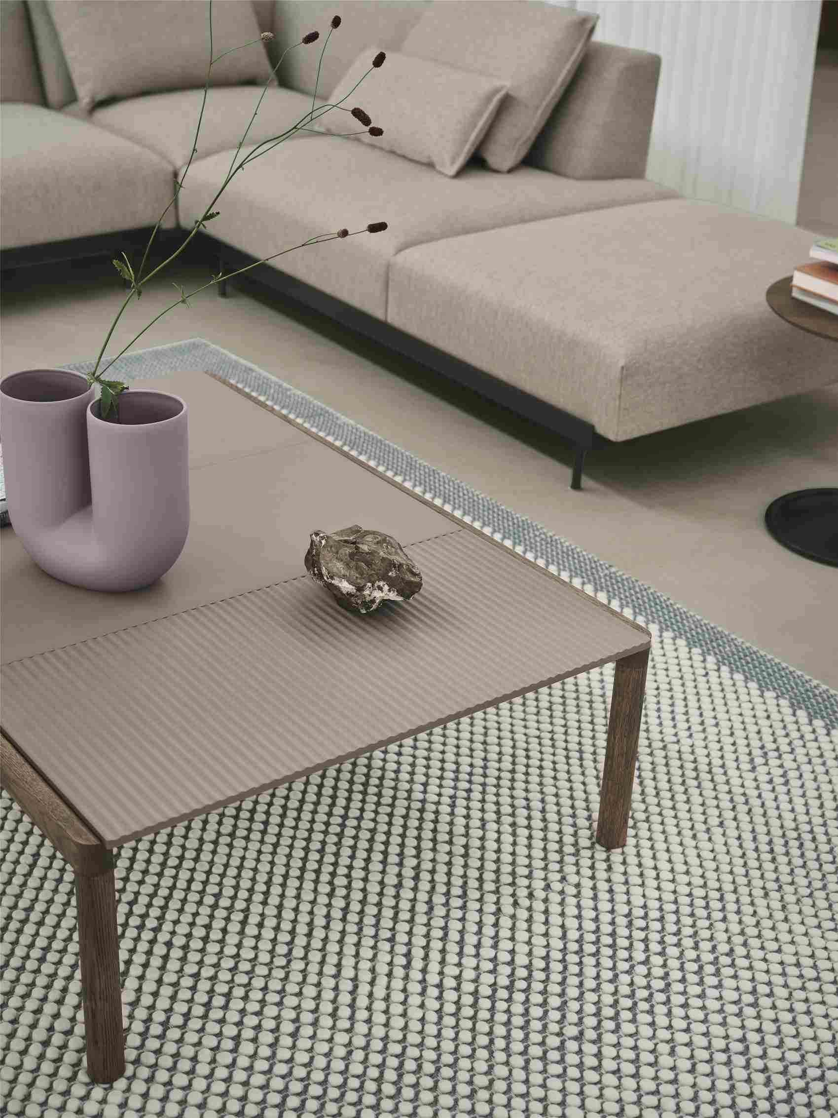 Muuto Couple Couchtisch aus Holz mit geriffelter Oberfläche und Deko-Elementen im Wohnzimmer.