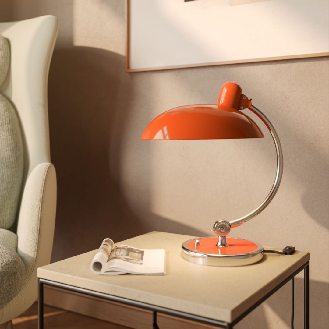 Orangefarbene Schreibtischlampe im Retro-Design auf einem Nachttisch mit Zeitschrift, ideal als Leselampe oder Bürolampe.