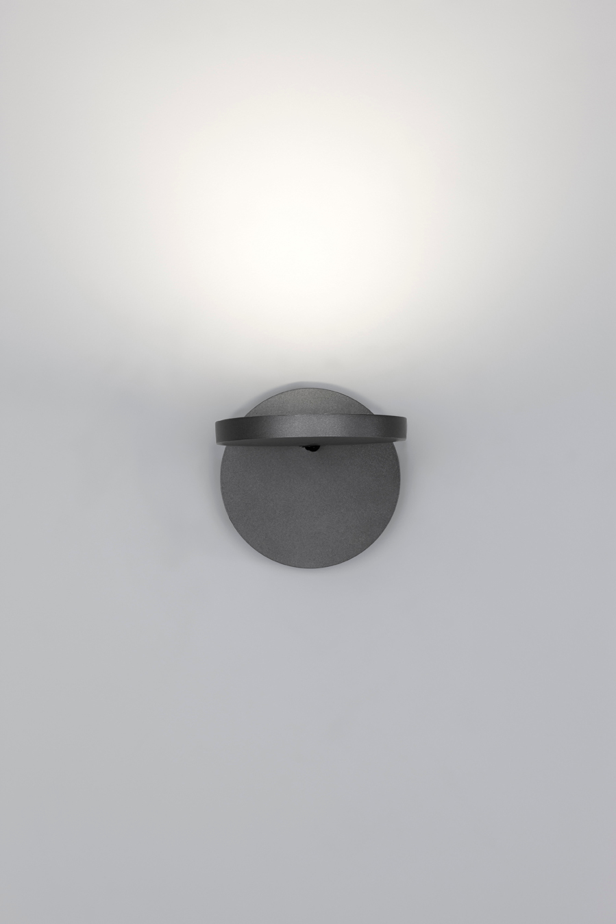 Nahaufnahme der grauen Demetra Wandleuchte von Artemide mit Schalter und warmem Lichtschein.