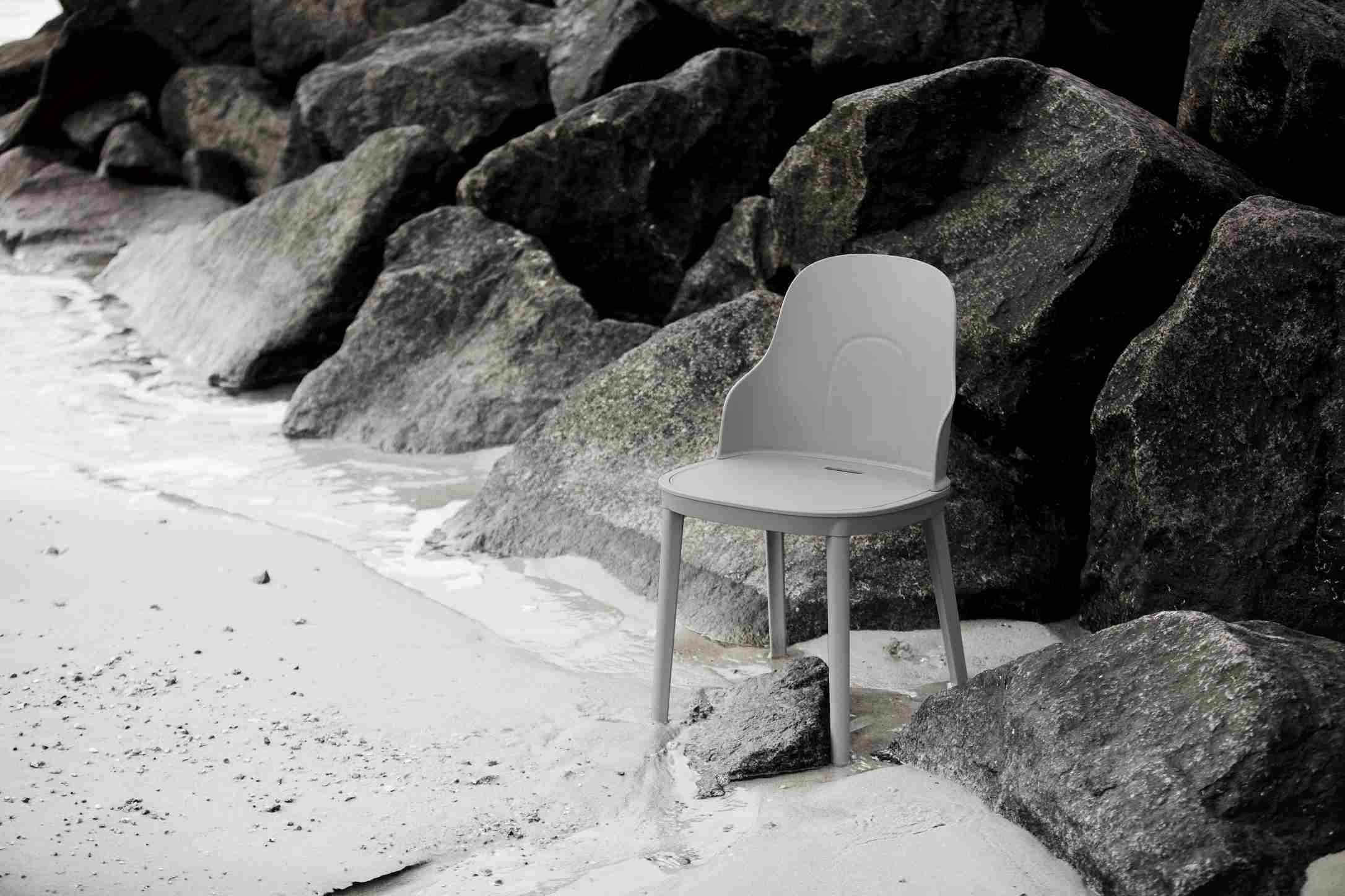 Grauer Allez Chair PP Stuhl von Normann Copenhagen steht am Strand vor dunklen Felsen.
