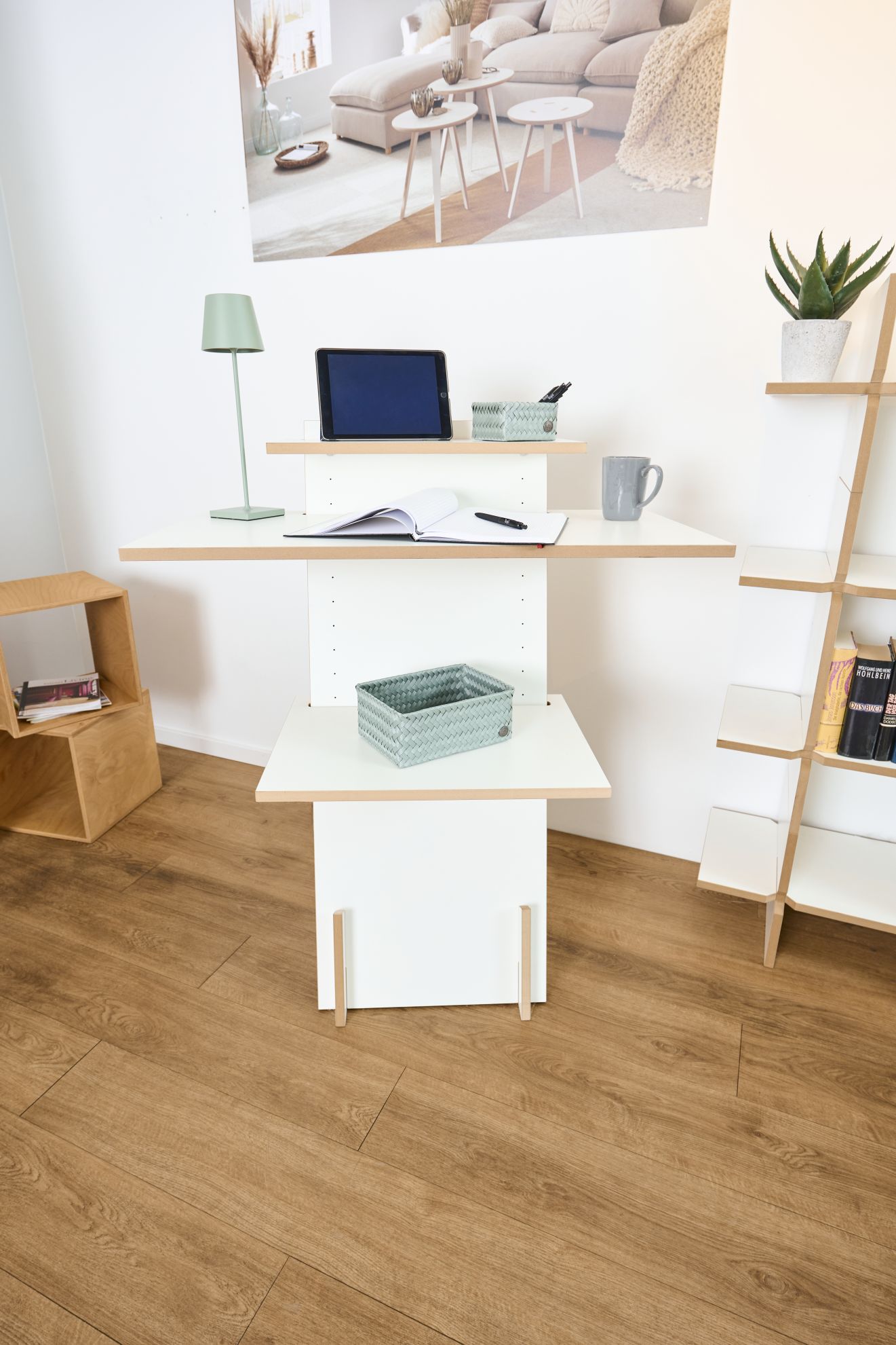 Moderner, weißer Stehschreibtisch mit Ablagen im Wohnzimmer, ideal für Homeoffice und platzsparendes Arbeiten.