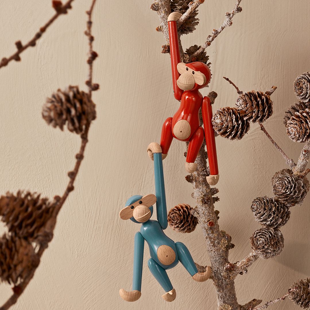 Buntes Kay Bojesen Mini Affe Holzspielzeug: Roter und blauer Deko Affe hängen an einem Ast.