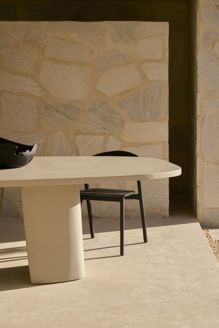 Canyon Outdoor Esstisch von Ethnicraft aus Beton mit Stuhl vor einer Steinwand.