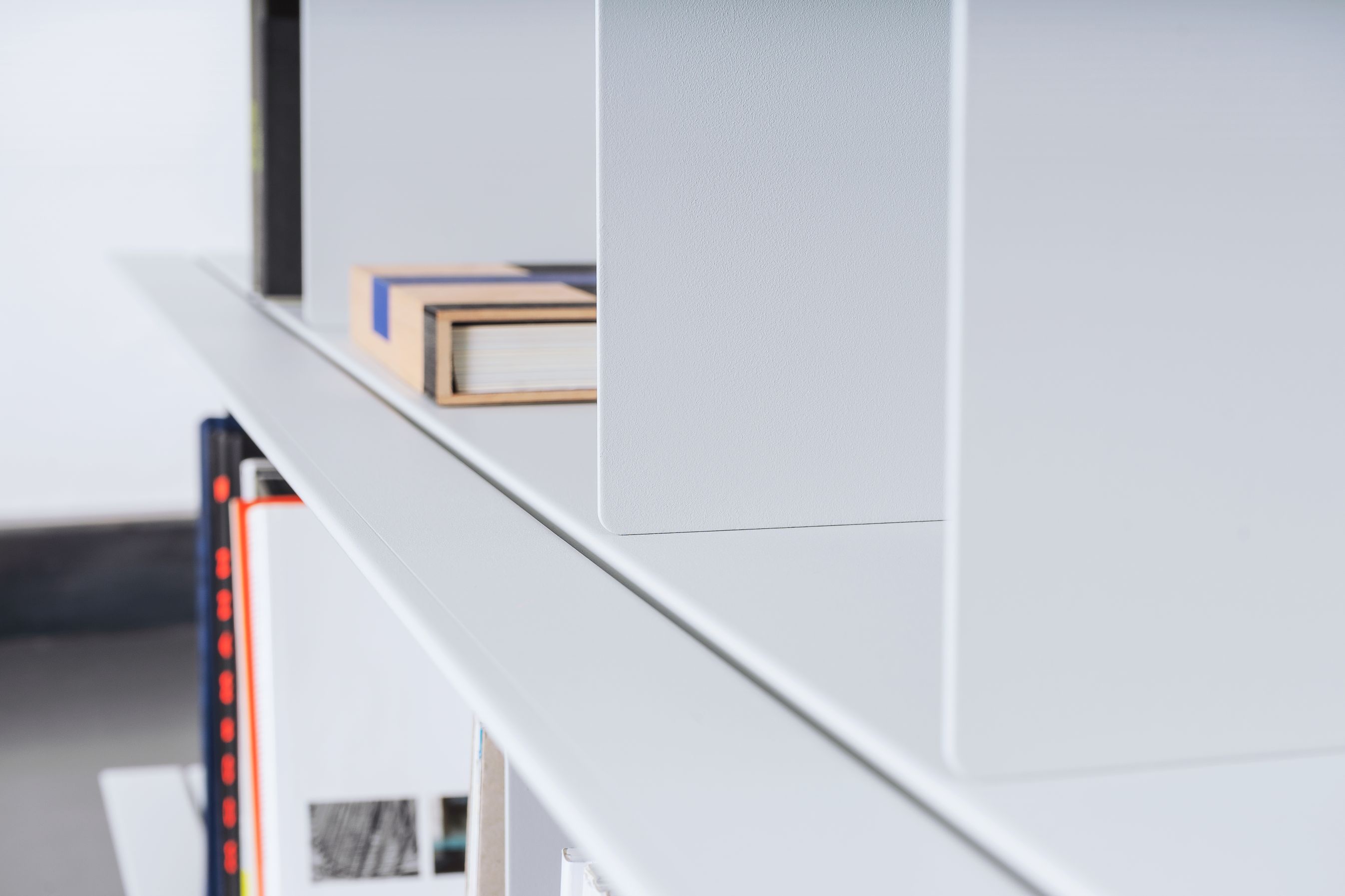 Detailaufnahme eines weißen Zoll D Regals von Nils Holger Moormann mit Büchern und minimalistischem Design.