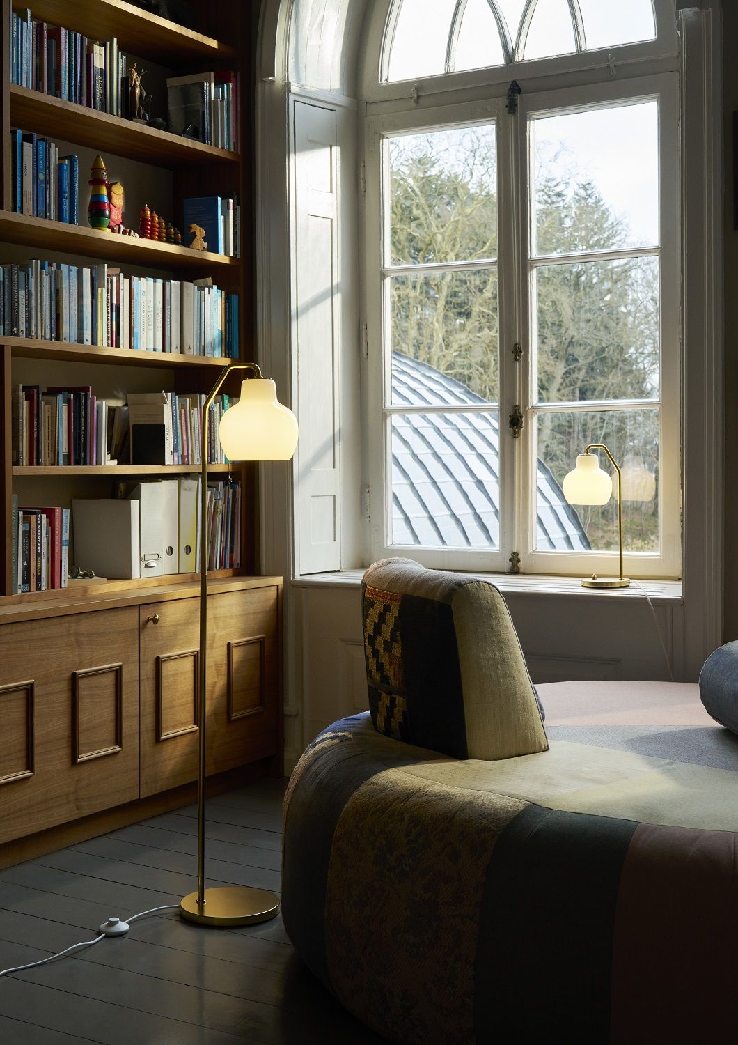 VL Ring Crown Stehleuchte von Louis Poulsen im Wohnzimmer mit Bücherregal und Fenster.