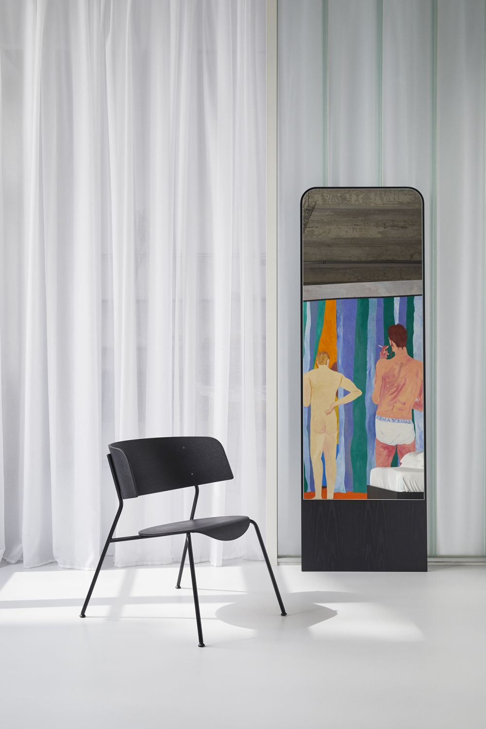 FRIEDRICH Spiegel Esche OUT im Interieur, reflektiert ein Gemälde, daneben ein schwarzer Stuhl vor einem Fenster.