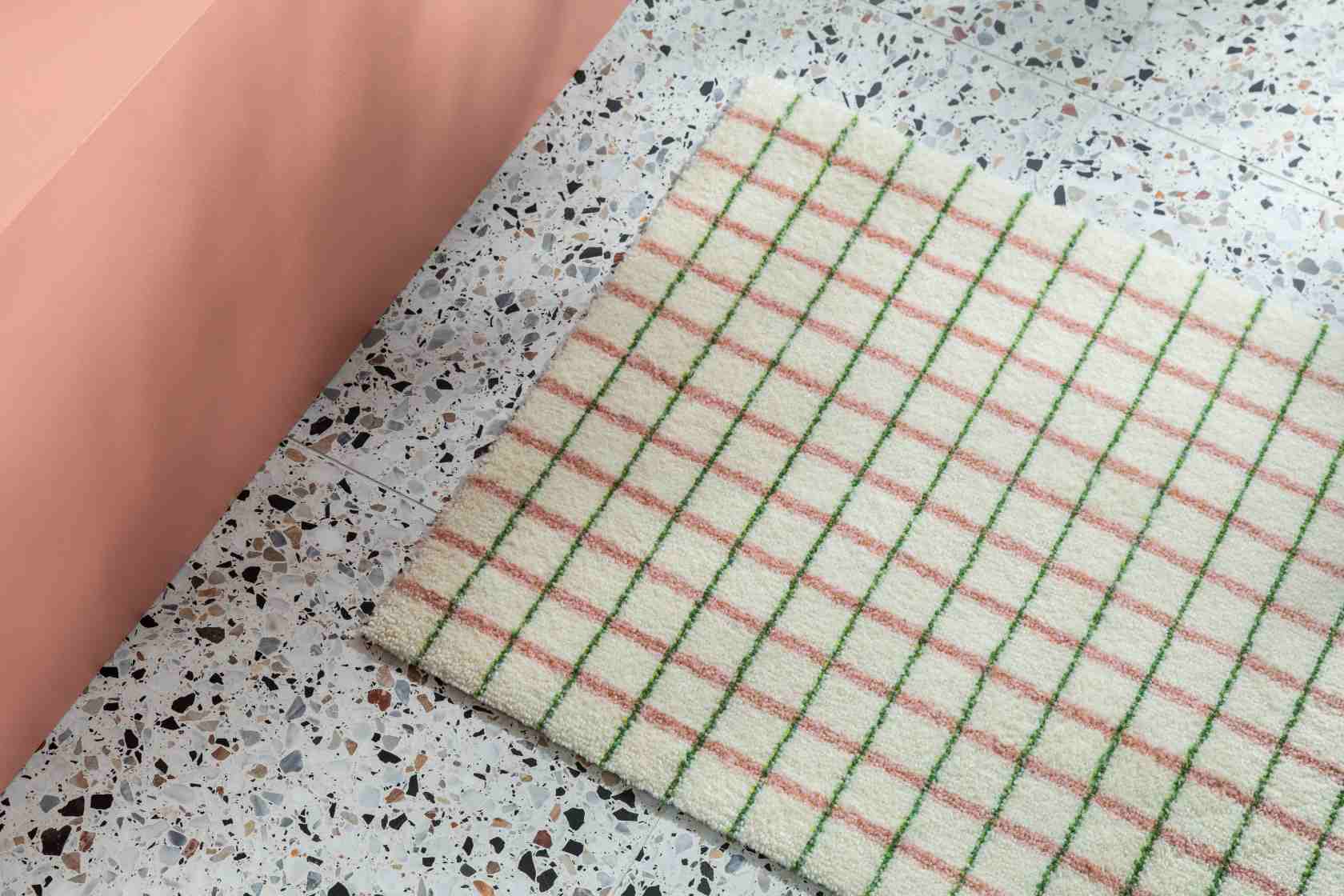 Grid Fußmatte "Lime Candycane" von Heymat: Weiße Schmutzfangmatte mit grün-rosa Karomuster auf Terrazzoboden.