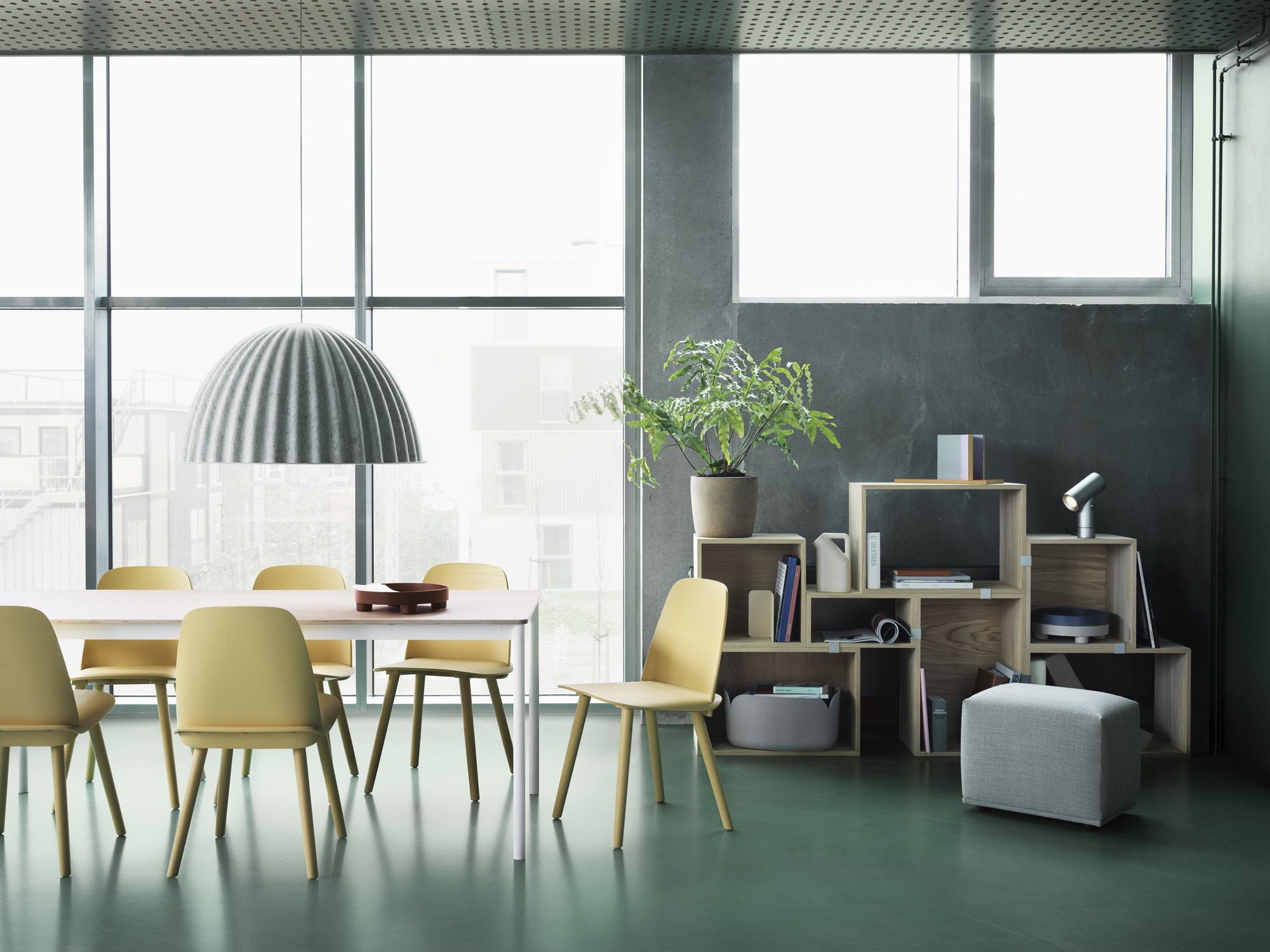 Modernes Esszimmer mit Muuto Stacked Storage Regalsystem, Esstisch mit gelben Stühlen und Hängelampe.