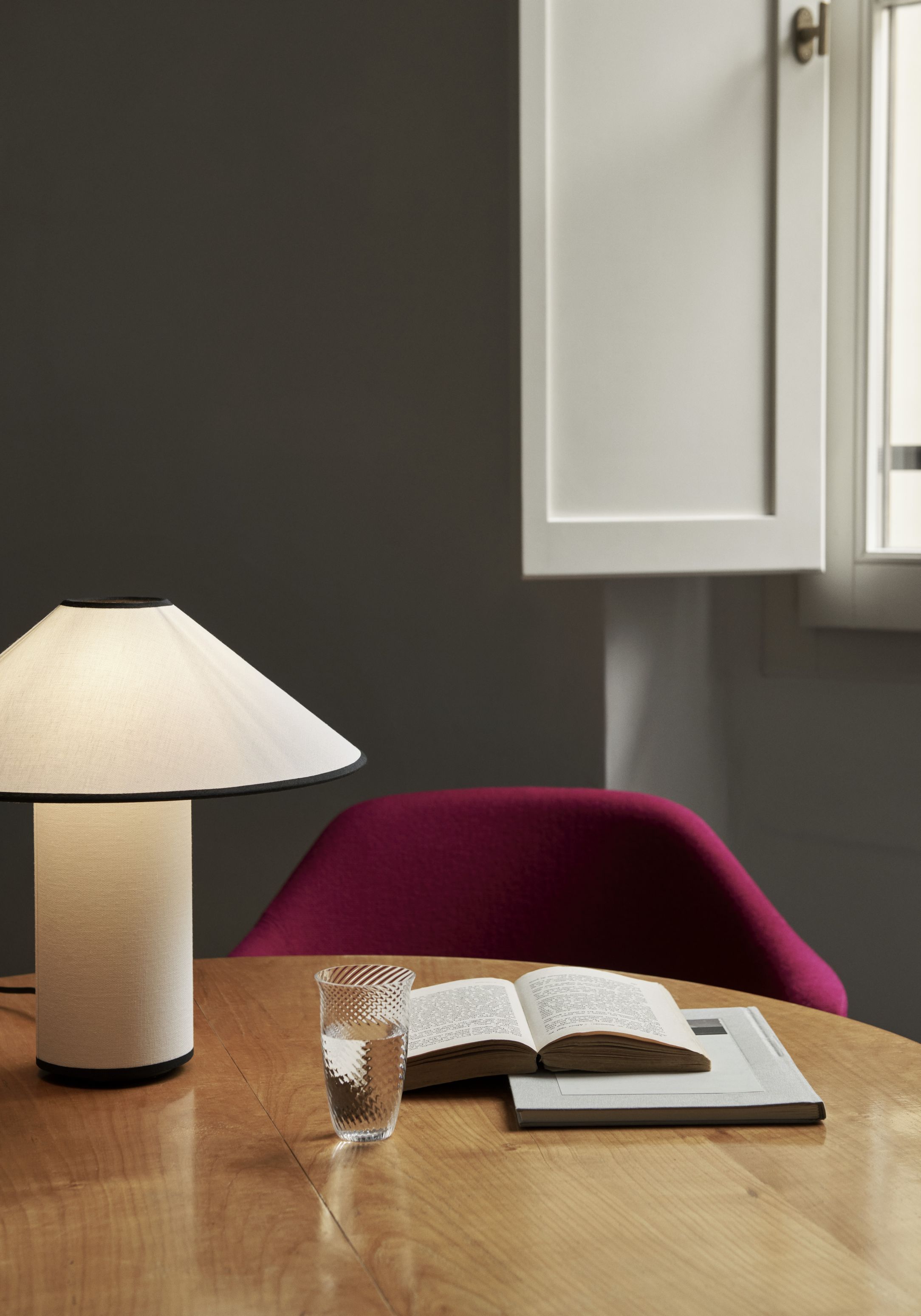 ATD6 Colette Tischleuchte von AndTradition auf Holztisch mit Buch und Glas. Design Lampe.