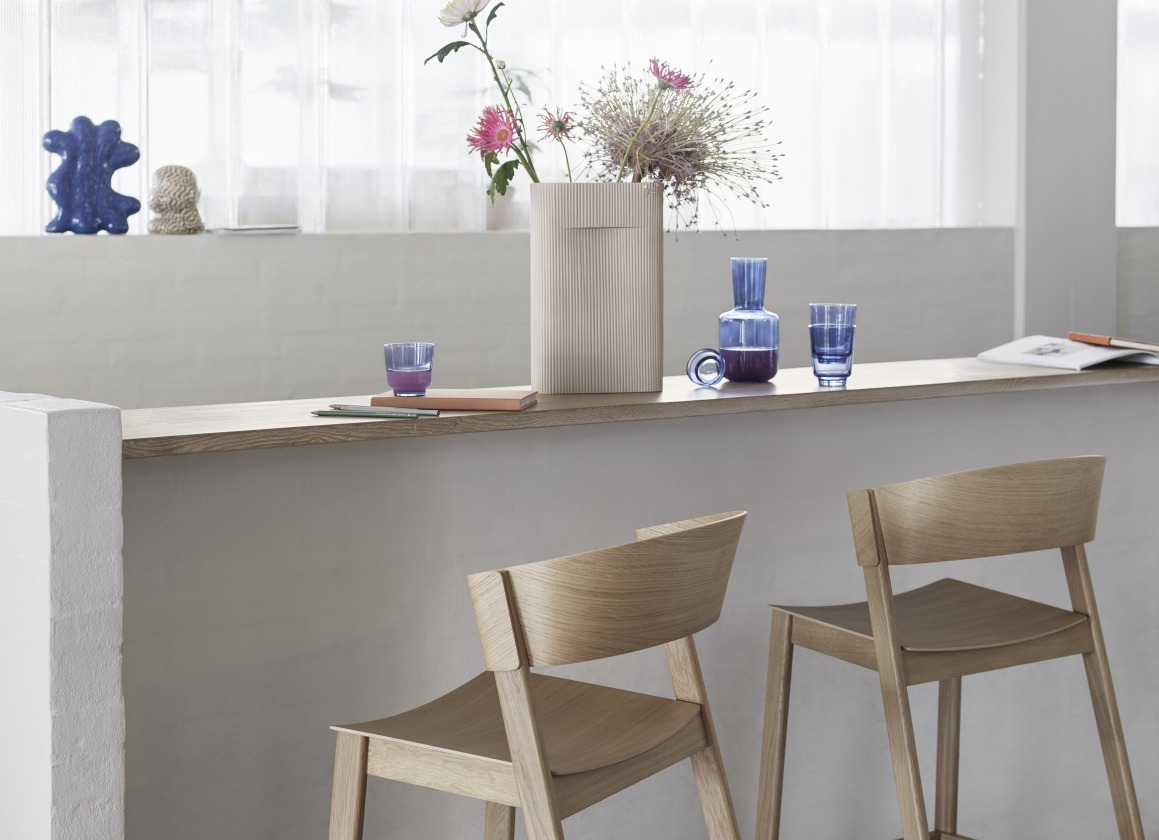 Zwei Cover Barstool Barhocker H 75 cm von Muuto aus hellem Holz vor Tresen.