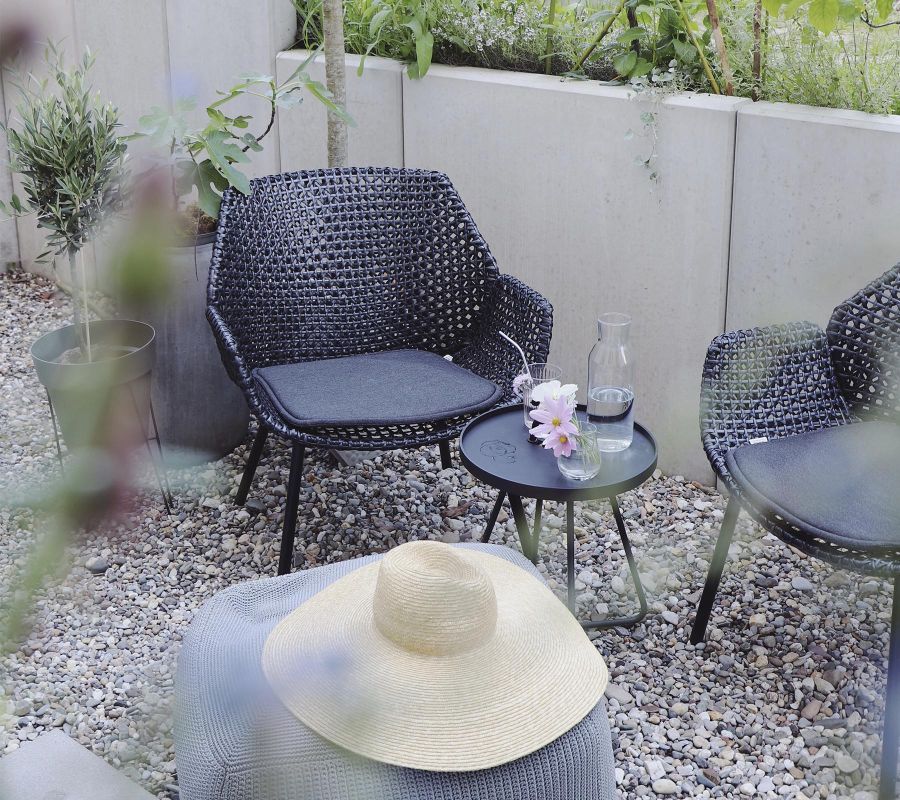 Cane-Line Vibe Highbacksessel aus Rattan mit Kissen und Beistelltisch im Garten.