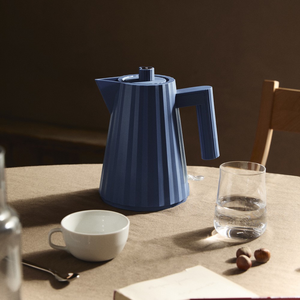Blauer Alessi Plissé Wasserkocher MDL06/1 auf Tisch mit Tasse und Glas.