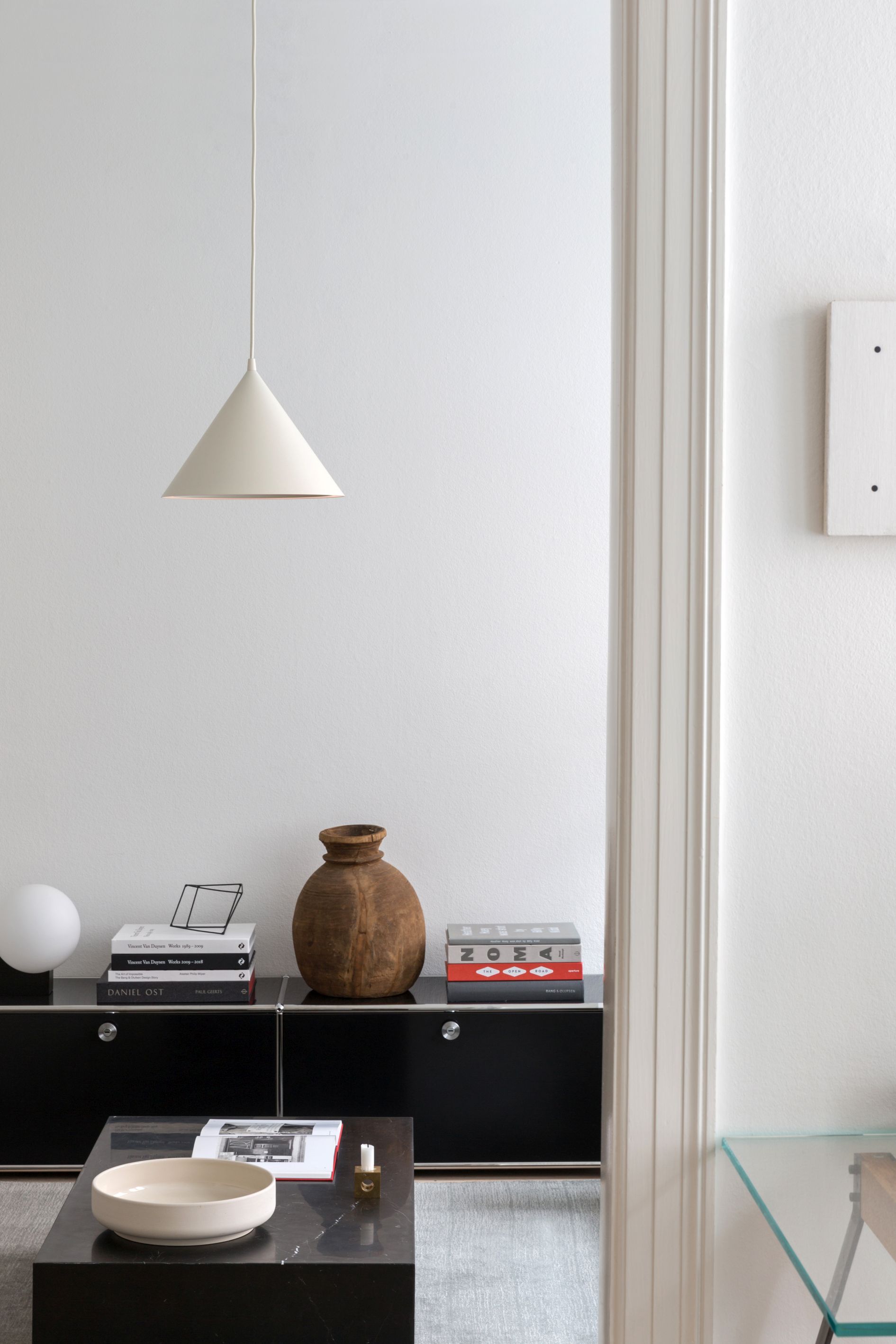 Annular Pendelleuchte von Woud, eine moderne Hängelampe in Weiß, die über einem Wohnzimmer-Setup hängt.