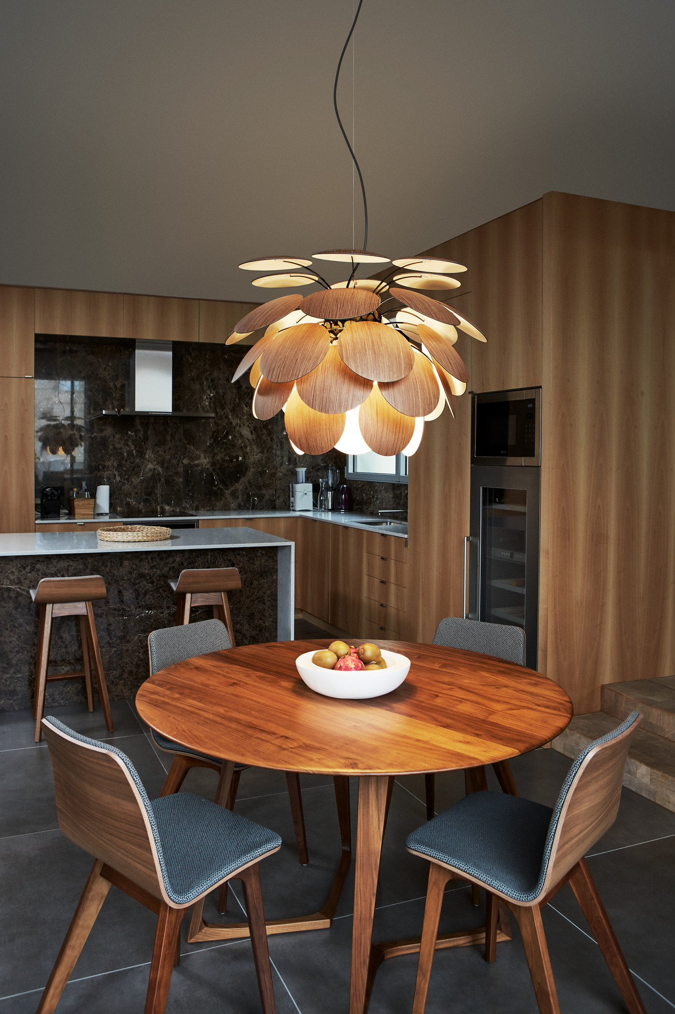 Discocó 68 Pendelleuchte in Schwarz-Gold über Esstisch. Moderne Designlampe für stilvolle Innenräume.