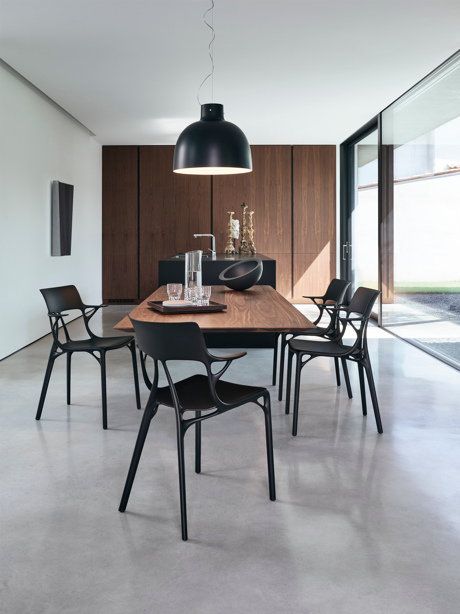 Innenaufnahme: Schwarze Kartell A.I. Stühle um einen Holztisch in modernem Esszimmer. Designermöbel.