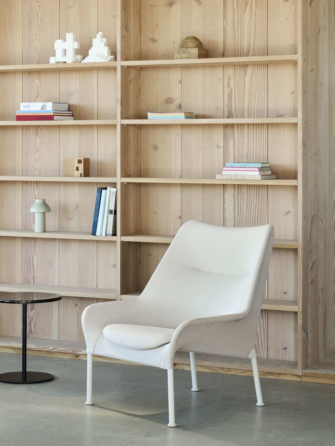 Heller Hay 02 Lounge Chair Sessel mit weißem Bezug und Beinen vor Holzregal.