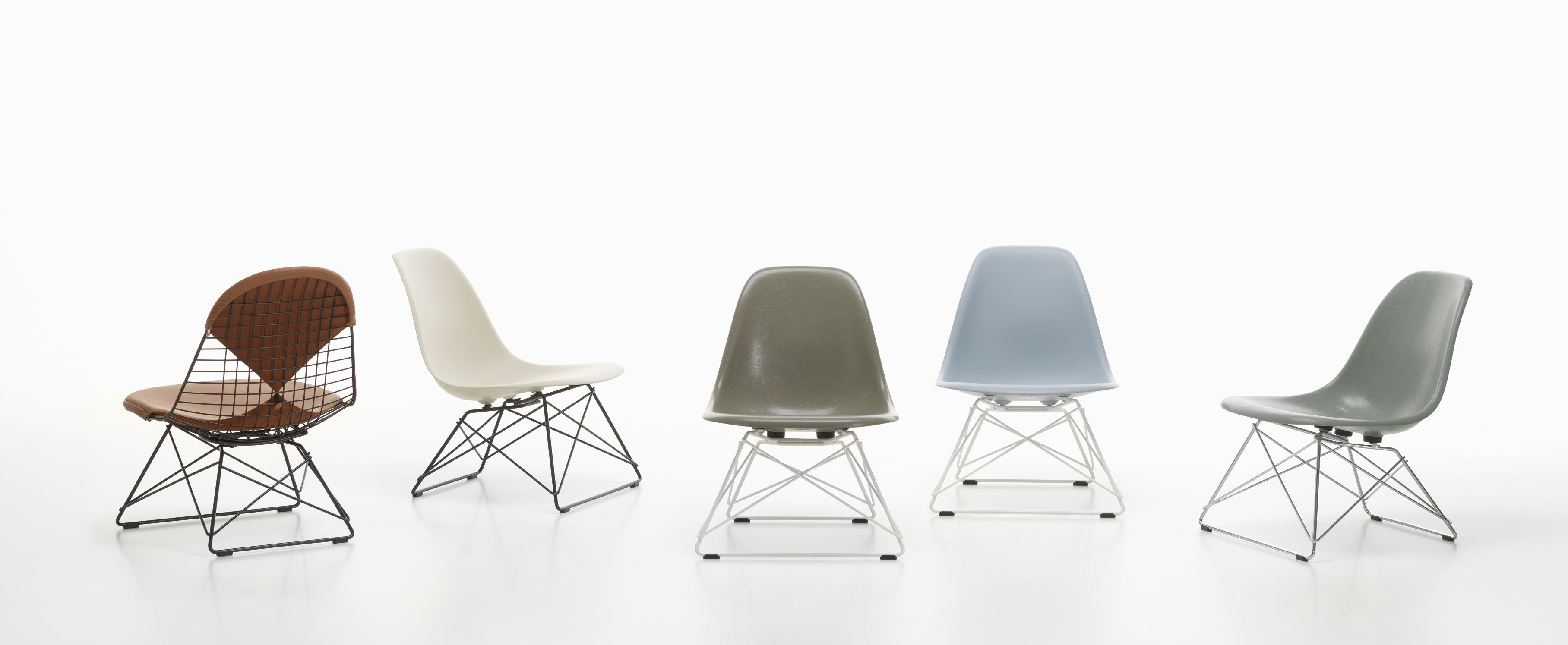 Fünf verschiedene Eames Plastic Side Chairs LSR Stühle von Vitra in einer Reihe auf weißem Hintergrund.