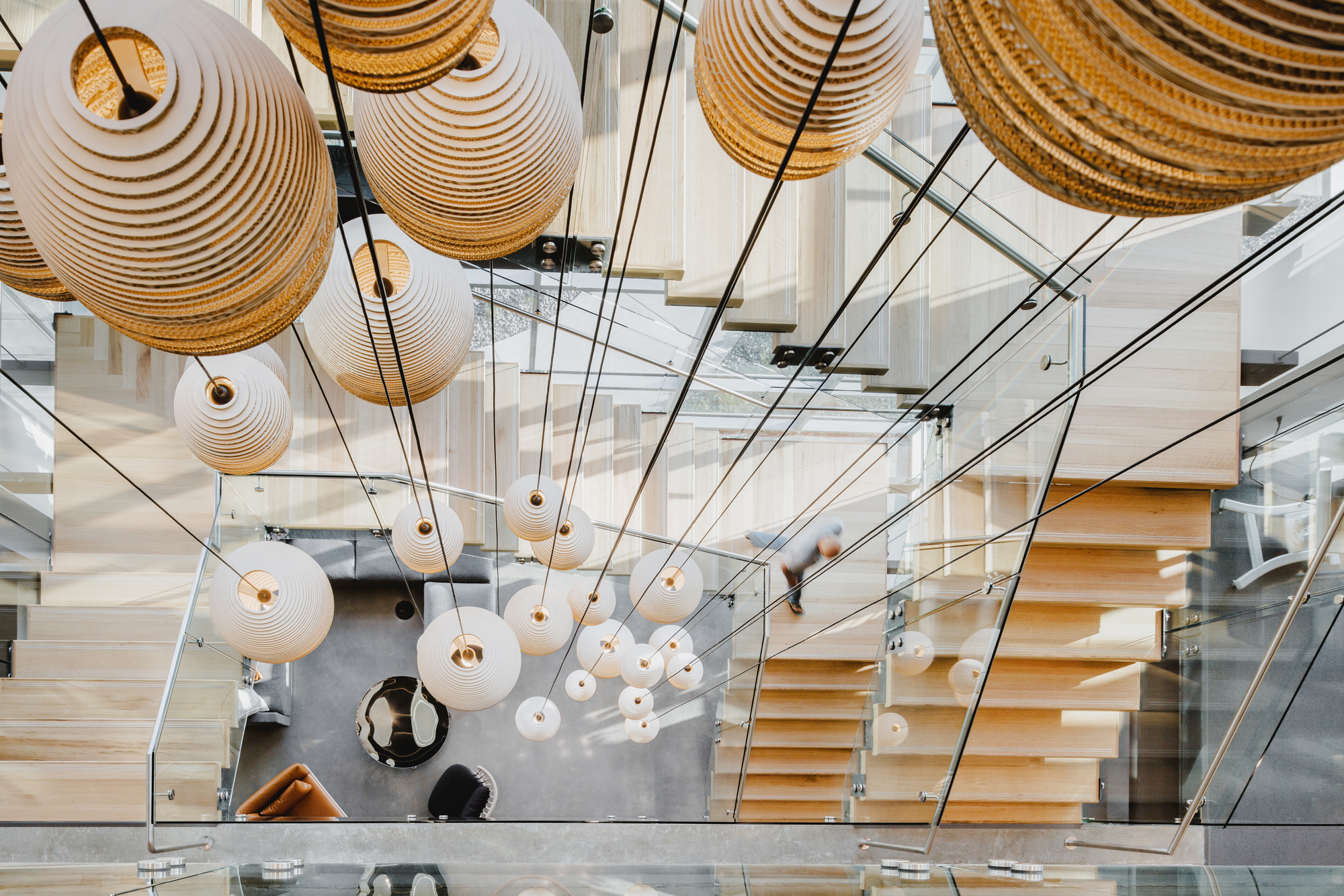 Ansicht von oben: Graypants Scraplights Hängeleuchten in Weiß über Treppe und Wohnbereich.