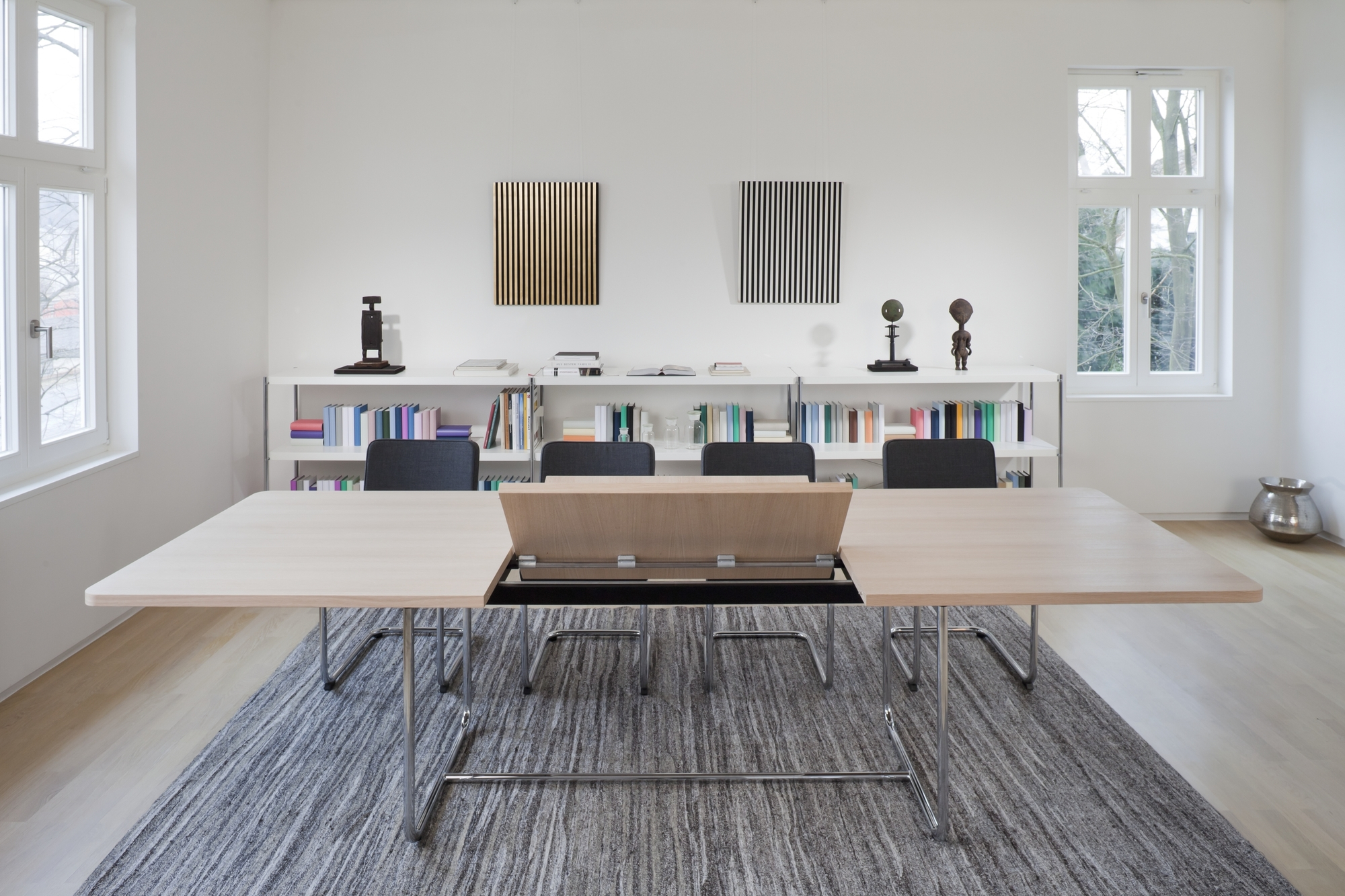 S 1072 Thonet Esstisch ausziehbar, helle Tischplatte, Chromgestell, moderne Büroeinrichtung mit Teppich und Regalen.