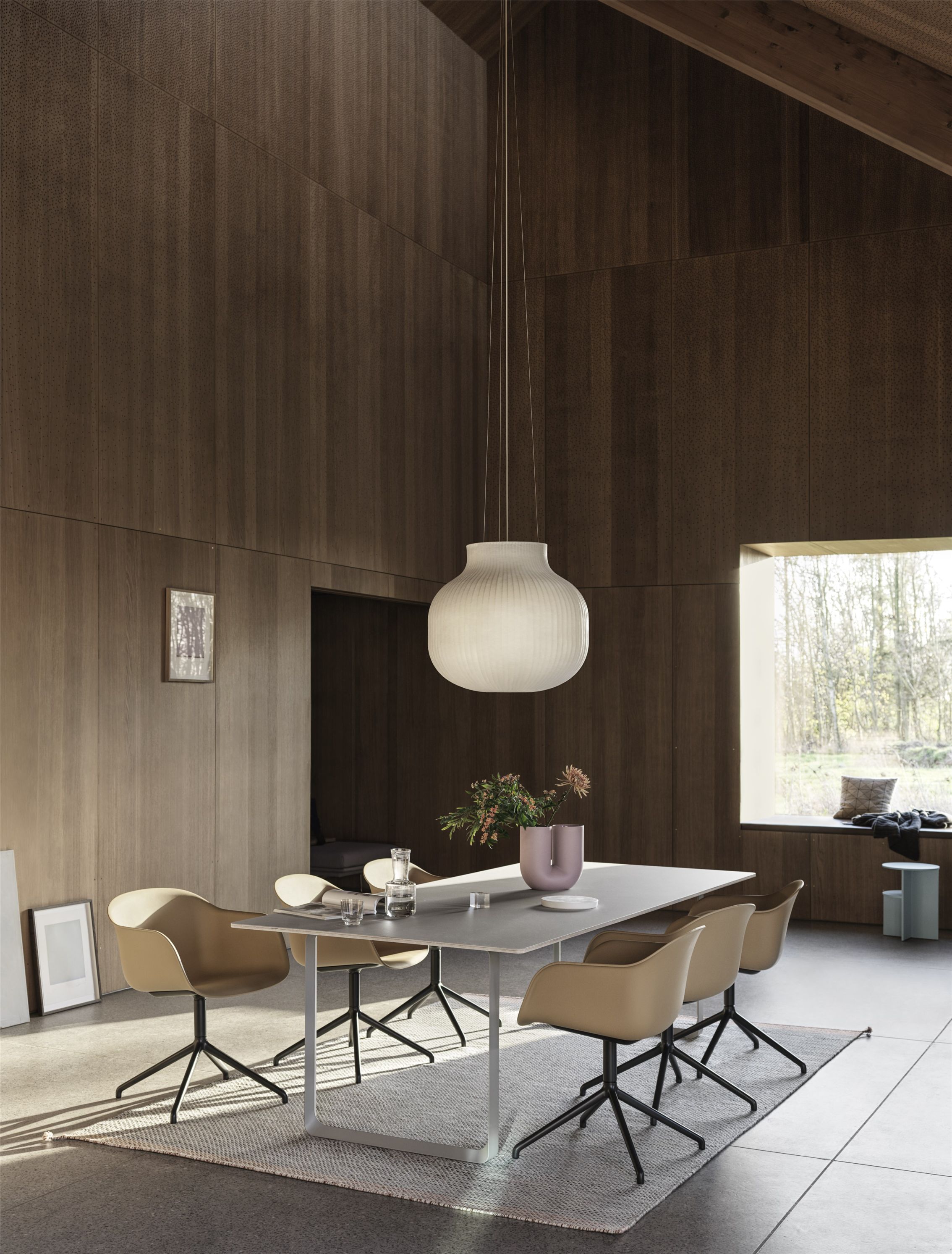 Esszimmer mit Muuto Fiber Armchair Stühlen, Drehfuss, grauem Tisch und moderner Lampe.
