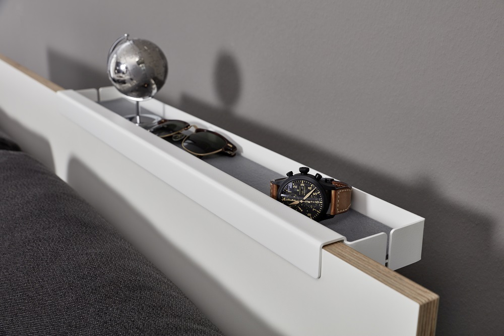 Flai Einzelbett von Müller Möbelwerkstätten mit Ablage für Uhr, Globus und Sonnenbrille.