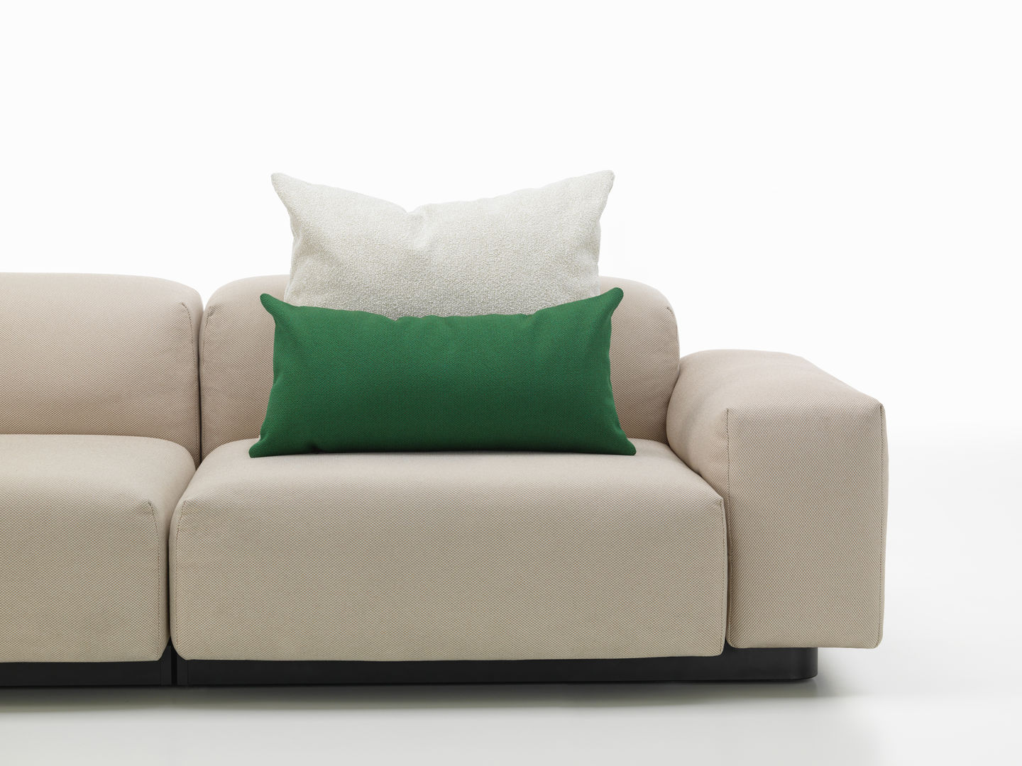 Beige Couch mit grünem und weißem Vitra Kissen, Sofakissen für Wohnzimmer und stilvolle Dekoration.