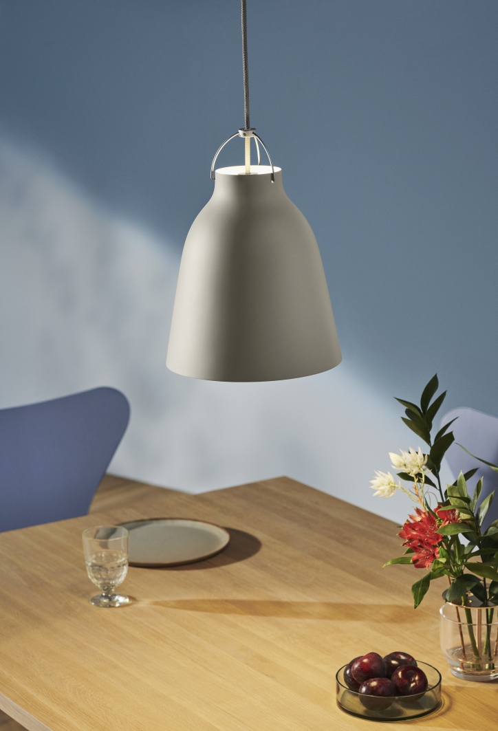 Graue Caravaggio Pendelleuchte von Fritz Hansen über einem Esstisch mit Geschirr und Blumenvase.