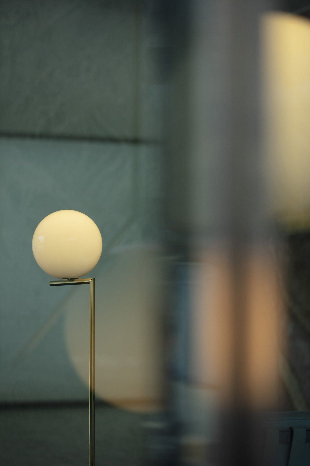 IC F1 Stehleuchte in Goldoptik von Flos mit runder, weißer Glaskugel als Leuchtmittel.