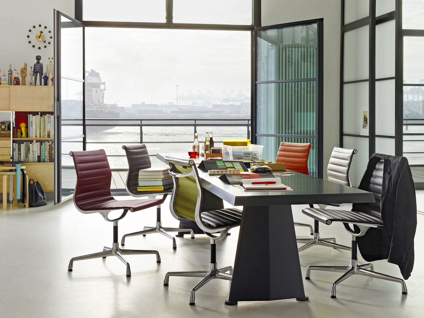 Aluminium Chair EA 104 von Vitra in verschiedenen Farben um einen Konferenztisch.