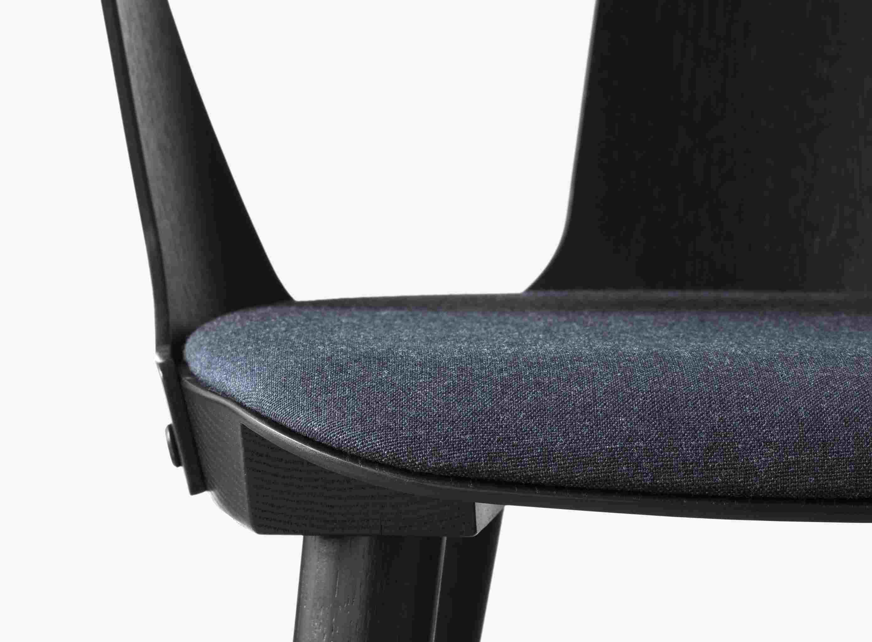 Detailaufnahme des In Between Armchair Armlehnenstuhls von AndTradition mit blauem Sitzpolster und dunklem Holzrahmen.