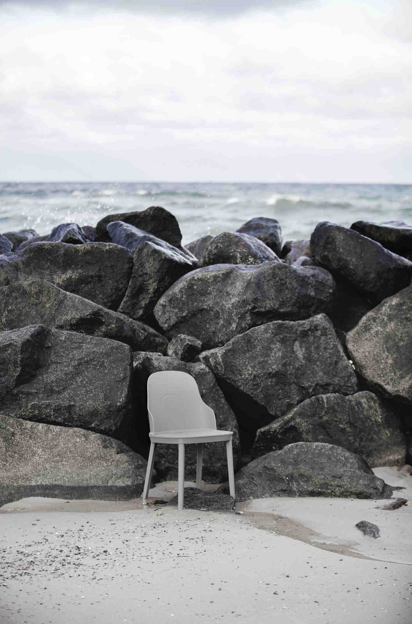 Heller Allez Chair Stuhl von Normann Copenhagen vor dunklen Felsen am Strand.