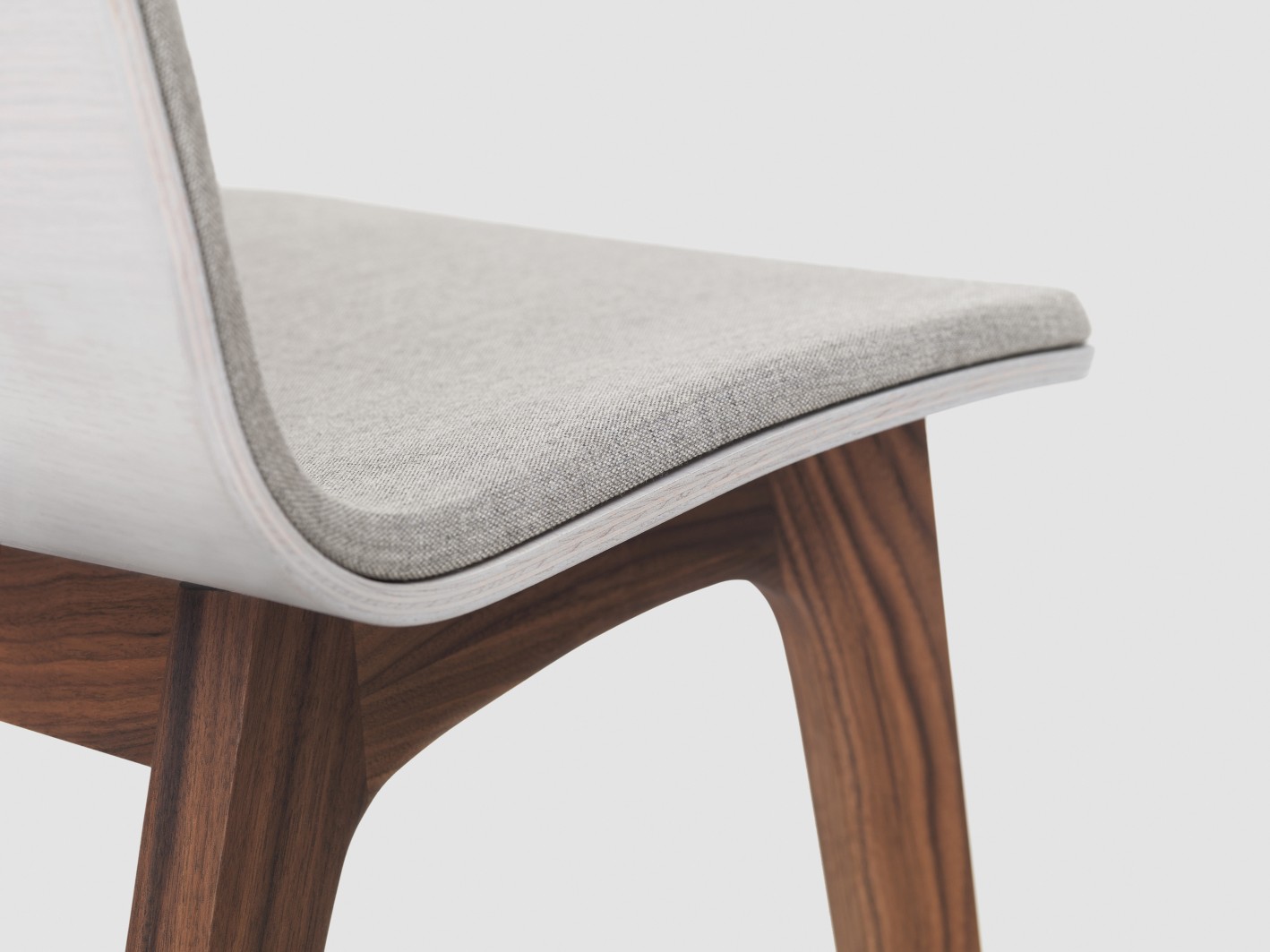 Detailaufnahme Morph Holzstuhl: Sitzpolster grau, Holzbeine Nussbaum, modernes Stuhldesign für Esszimmer.