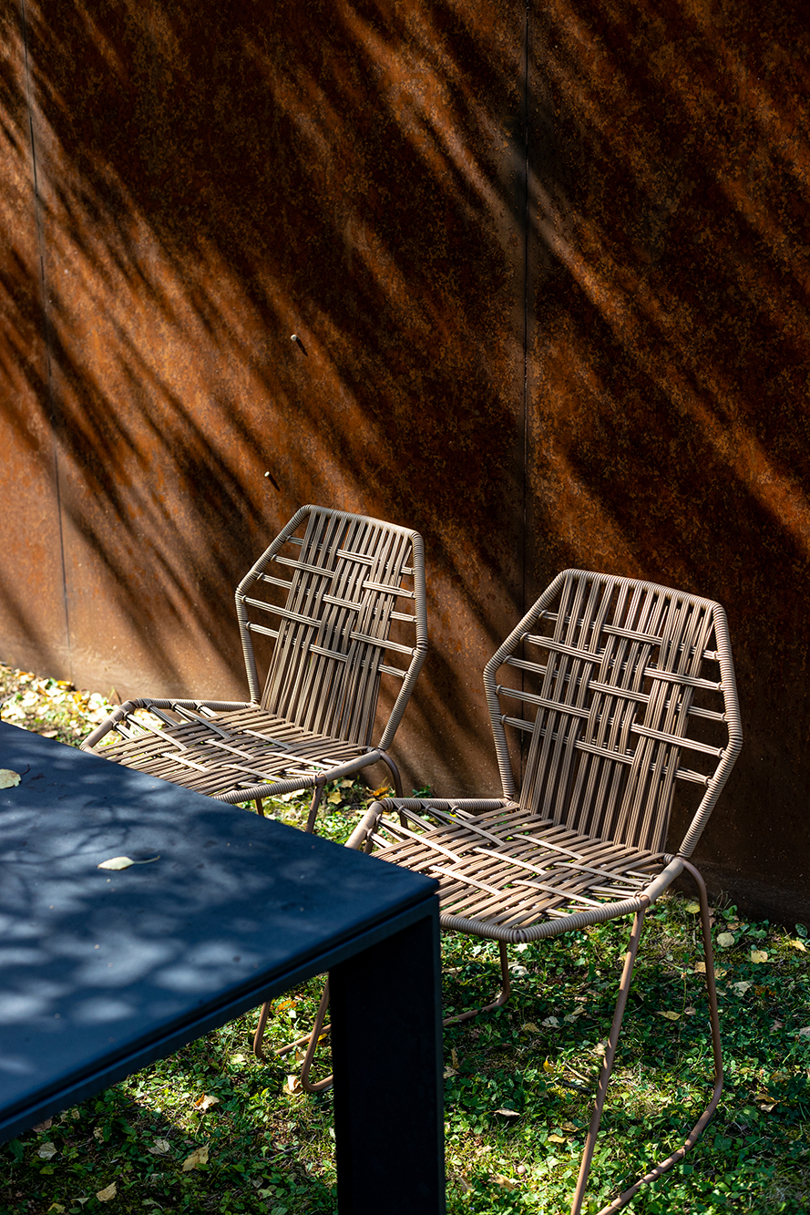 Zwei Tropicalia TR0 Outdoor Stühle aus Polymer von Moroso neben einem Tisch im Garten.