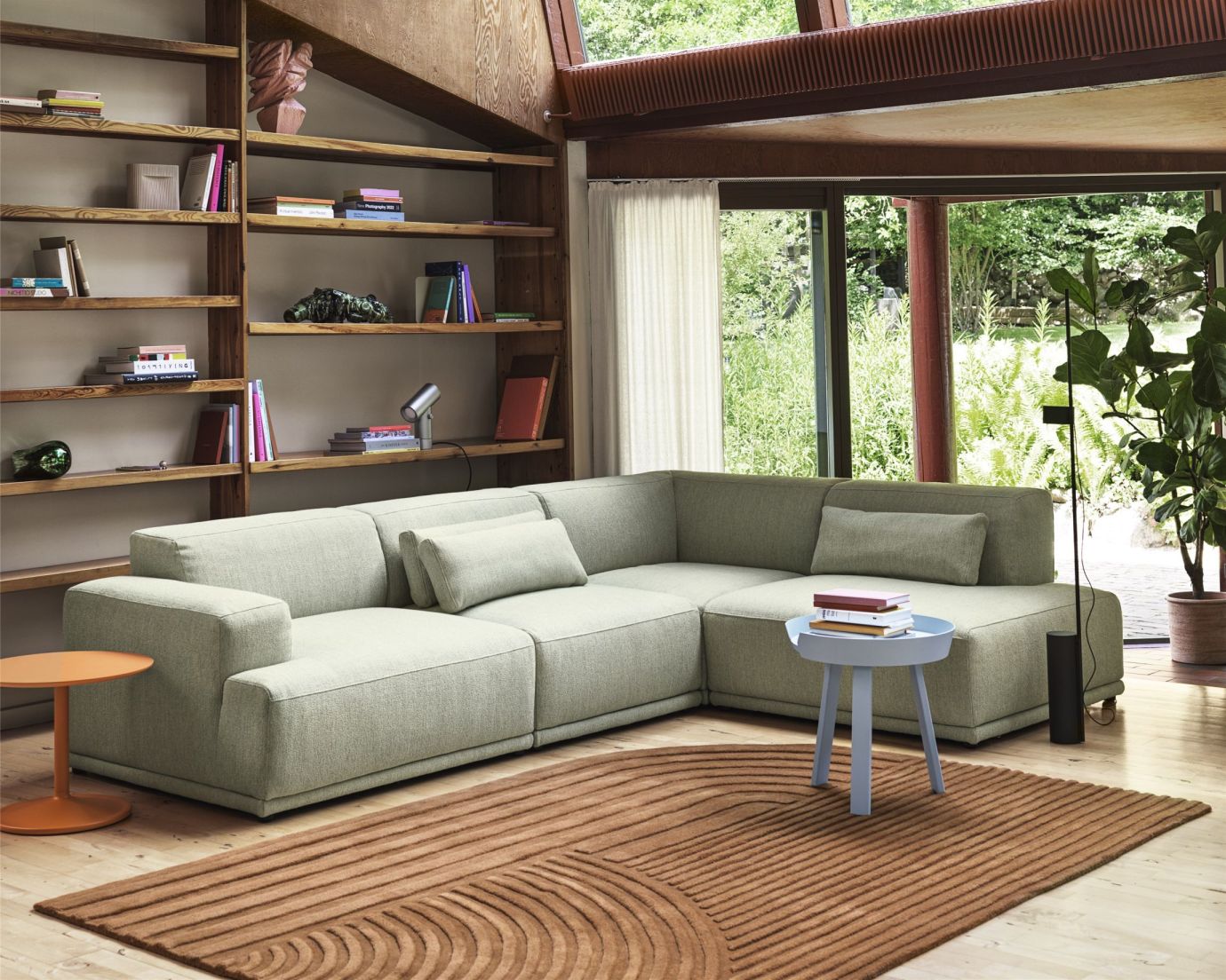 Helle, moderne Eckcouch in Wohnzimmer mit Teppich und Bücherregal. Gemütliche Wohnlandschaft für entspanntes Wohnen.