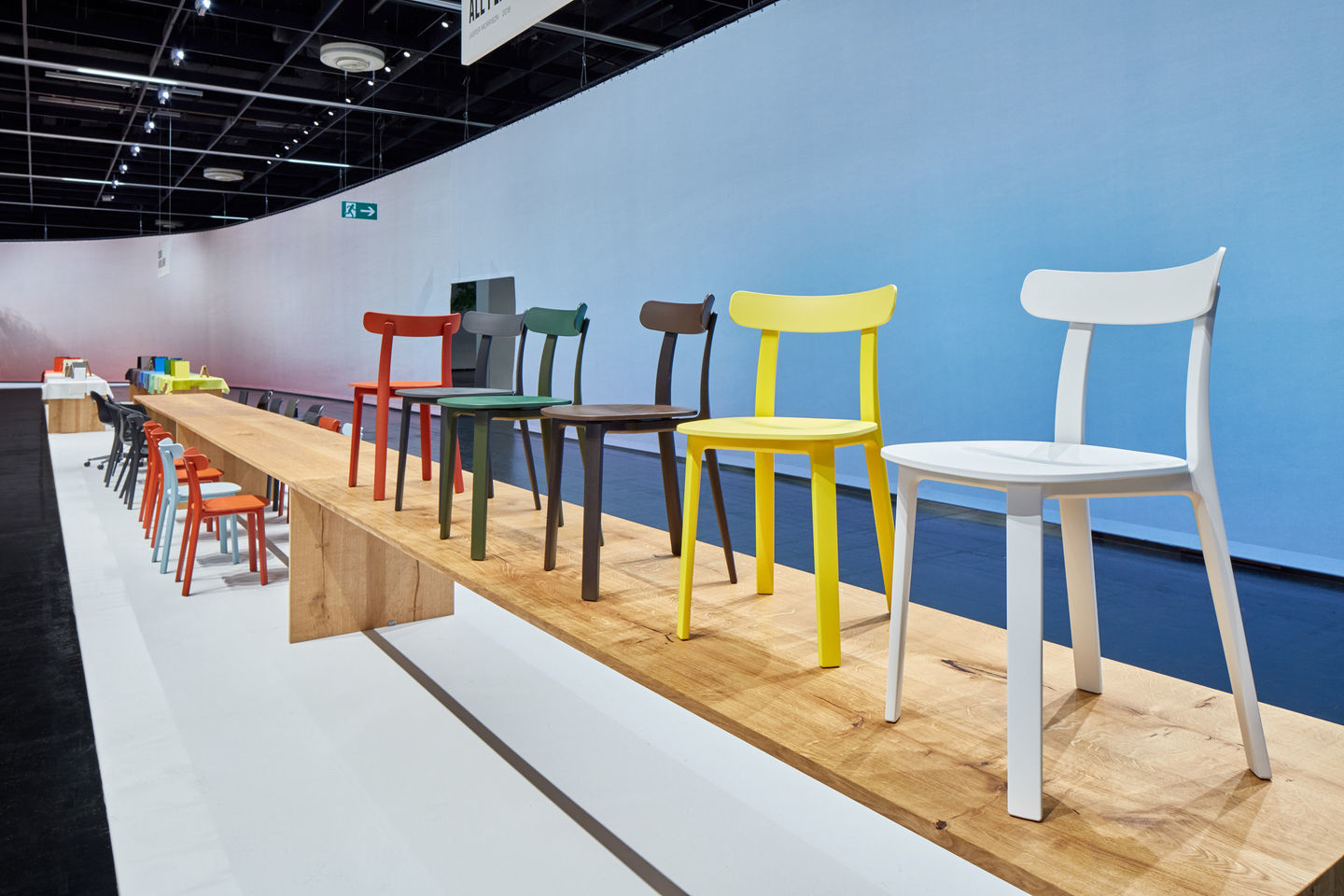 Vitra All Plastic Chair Outdoor Stuhl in verschiedenen Farben auf einem Holzpodest, modernes Möbeldesign.