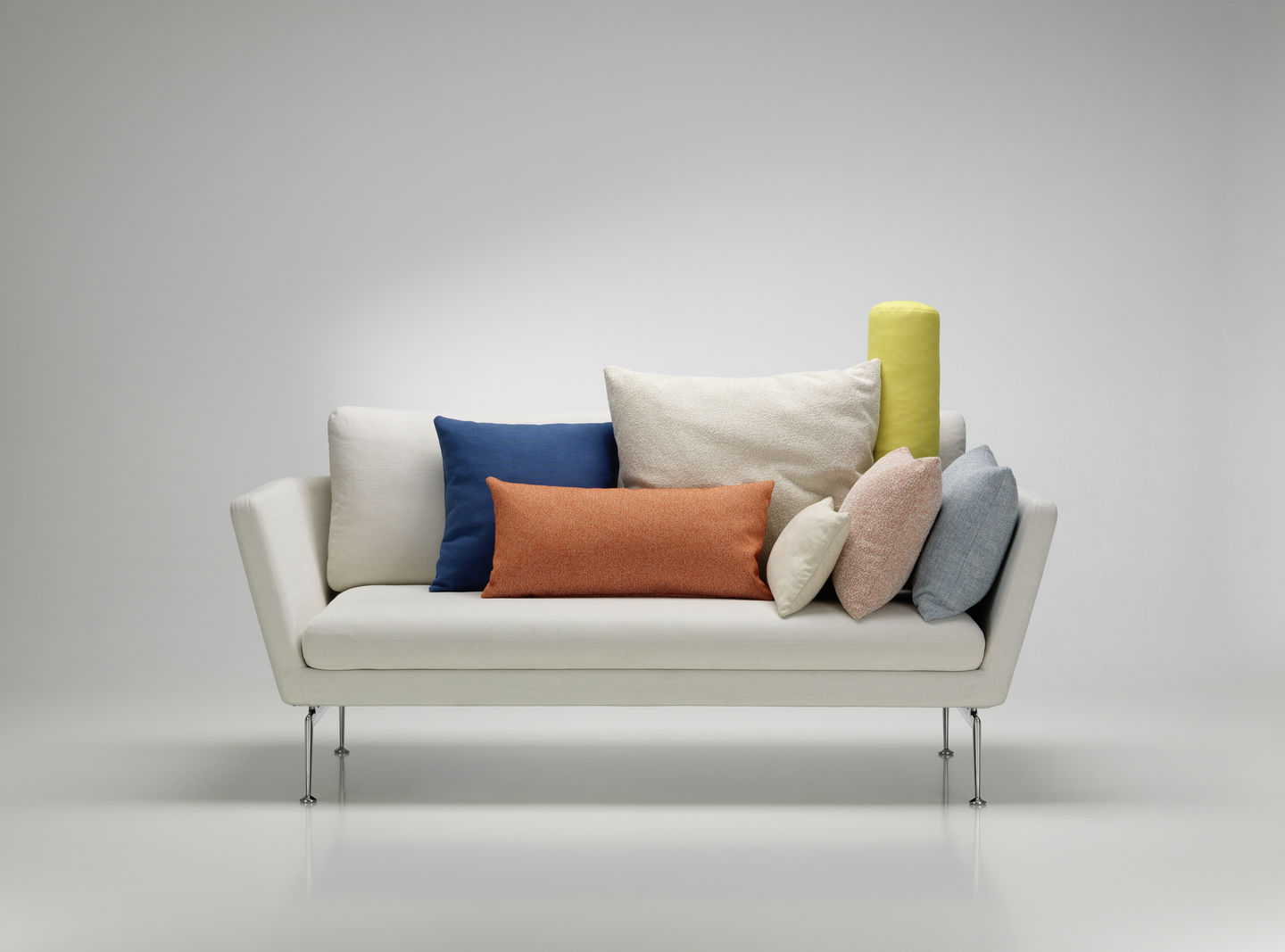Weißes Sofa mit verschiedenen farbigen Vitra Kissen und Sofakissen in Blau, Orange, Beige und Gelb.